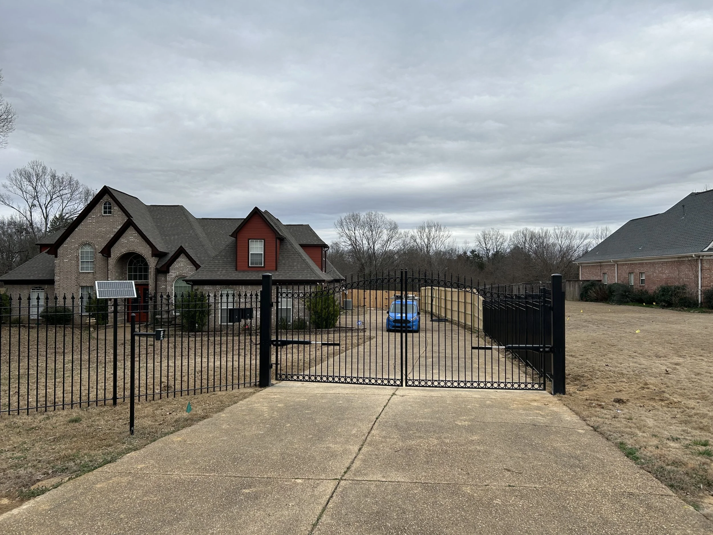 Double ornamental steel driveway gate with matching ornamental fencing installed at a residential property in Olive Branch, Mississippi by DeSoto Fence Co.