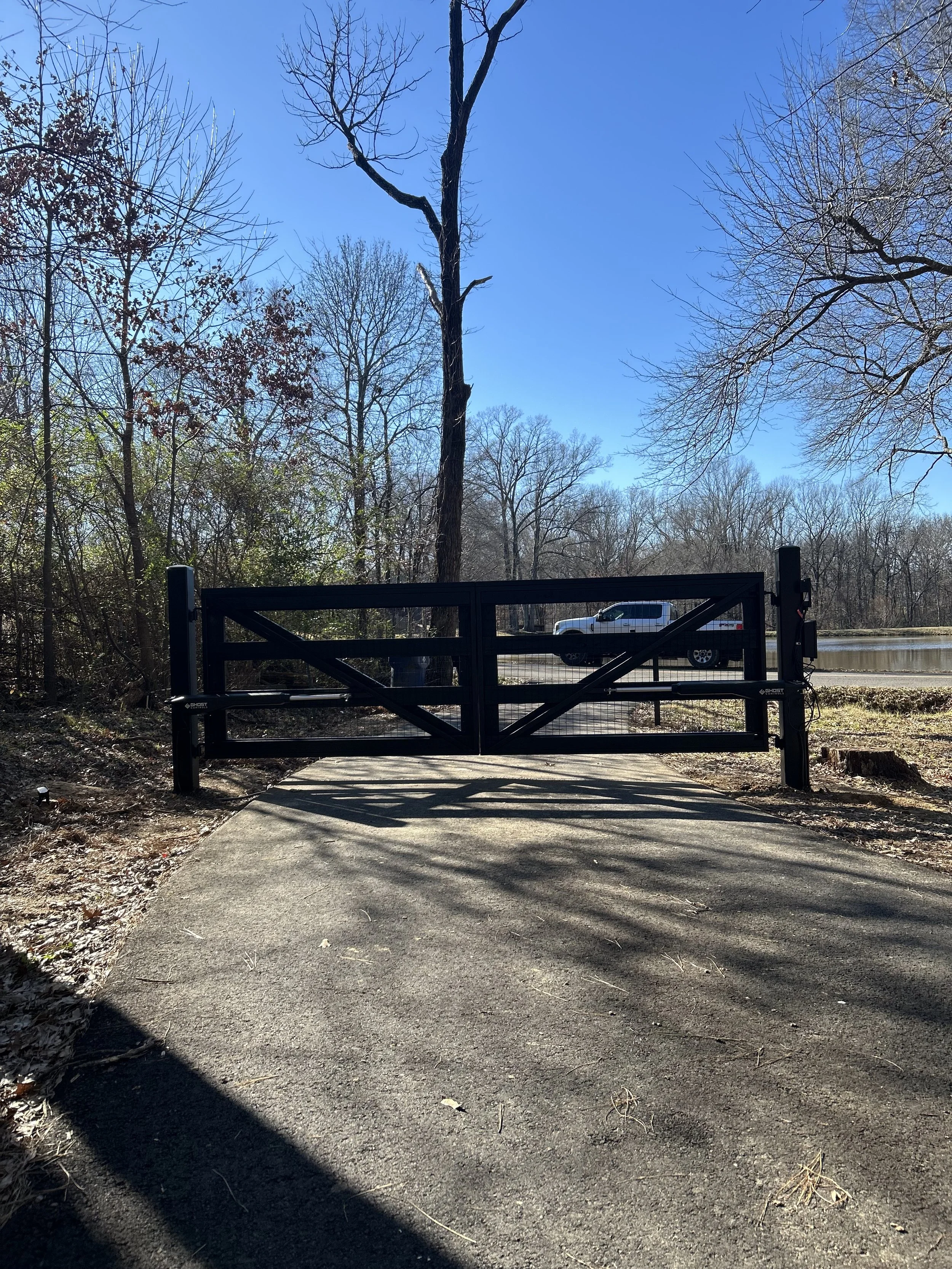 Rear view of a custom black crossbuck driveway gate with Ghost Controls automatic gate operators in Hernando, MS.