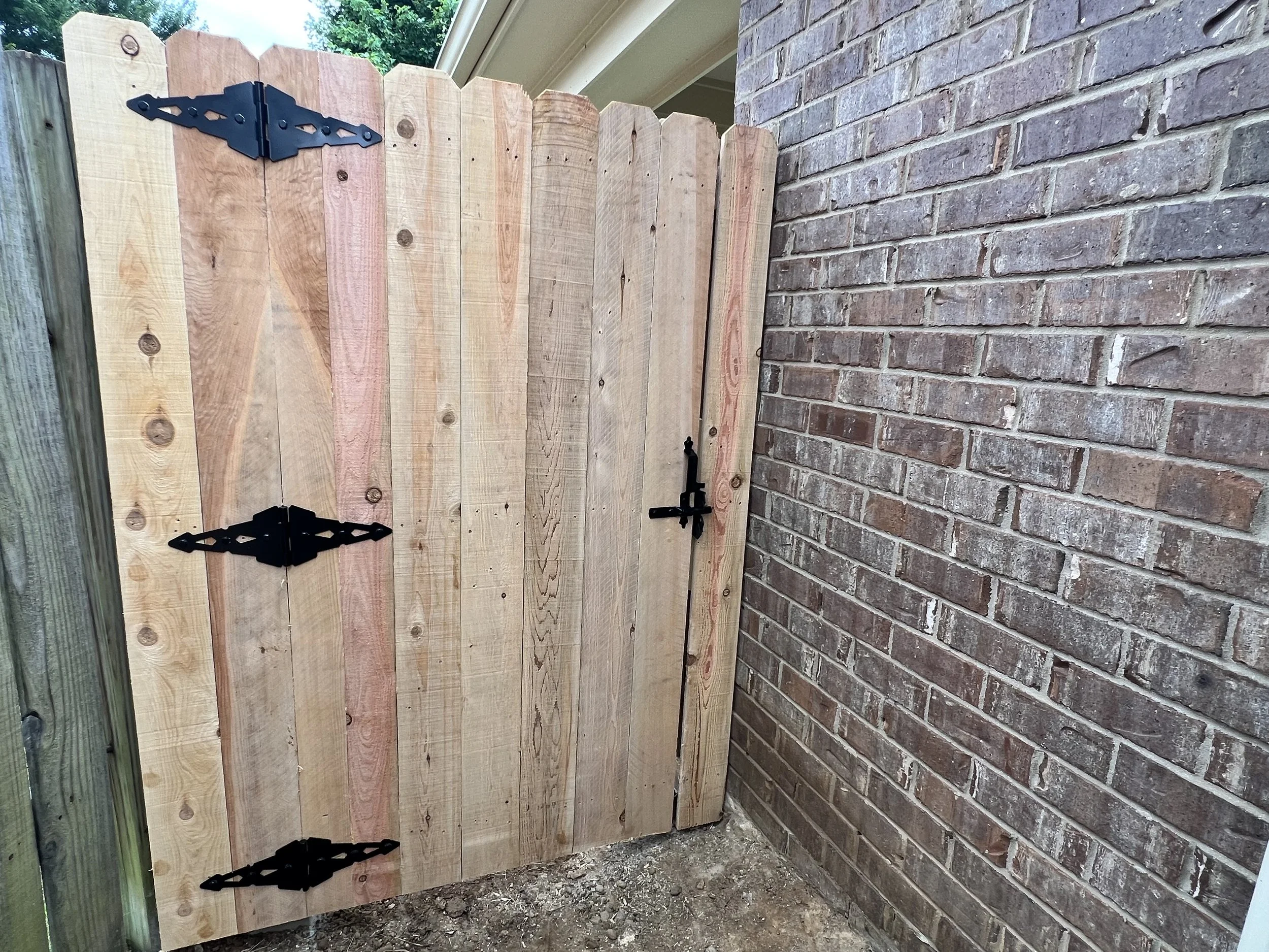 Cedar privacy fence with custom single gate installed in Hernando, MS. This section shows clean picket alignment, black hardware, and a tight gate fit for durability and everyday use.
