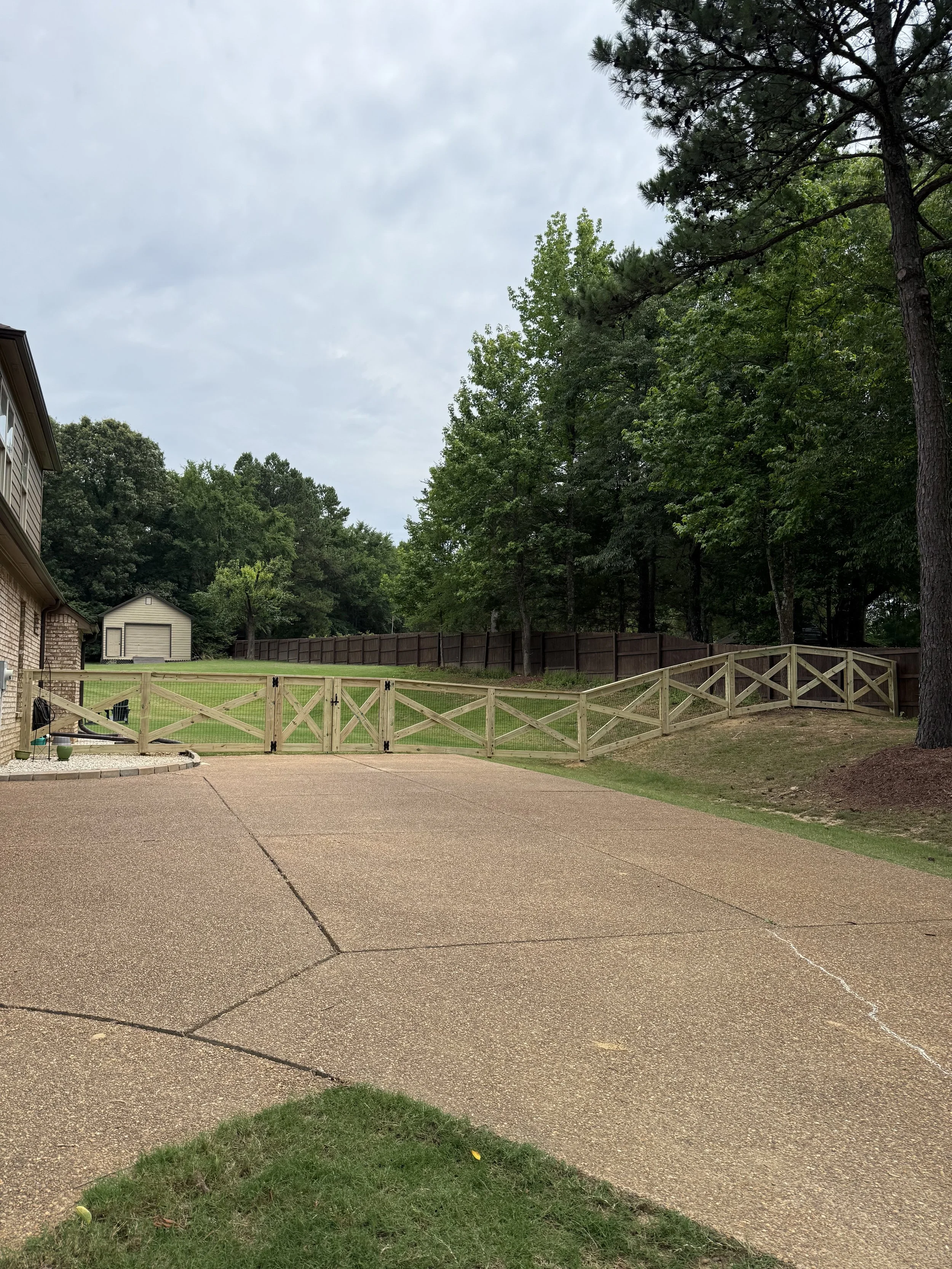 Custom crossbuck driveway gates with welded wire fencing installed at a residential property in Olive Branch, Mississippi by DeSoto Fence Co.