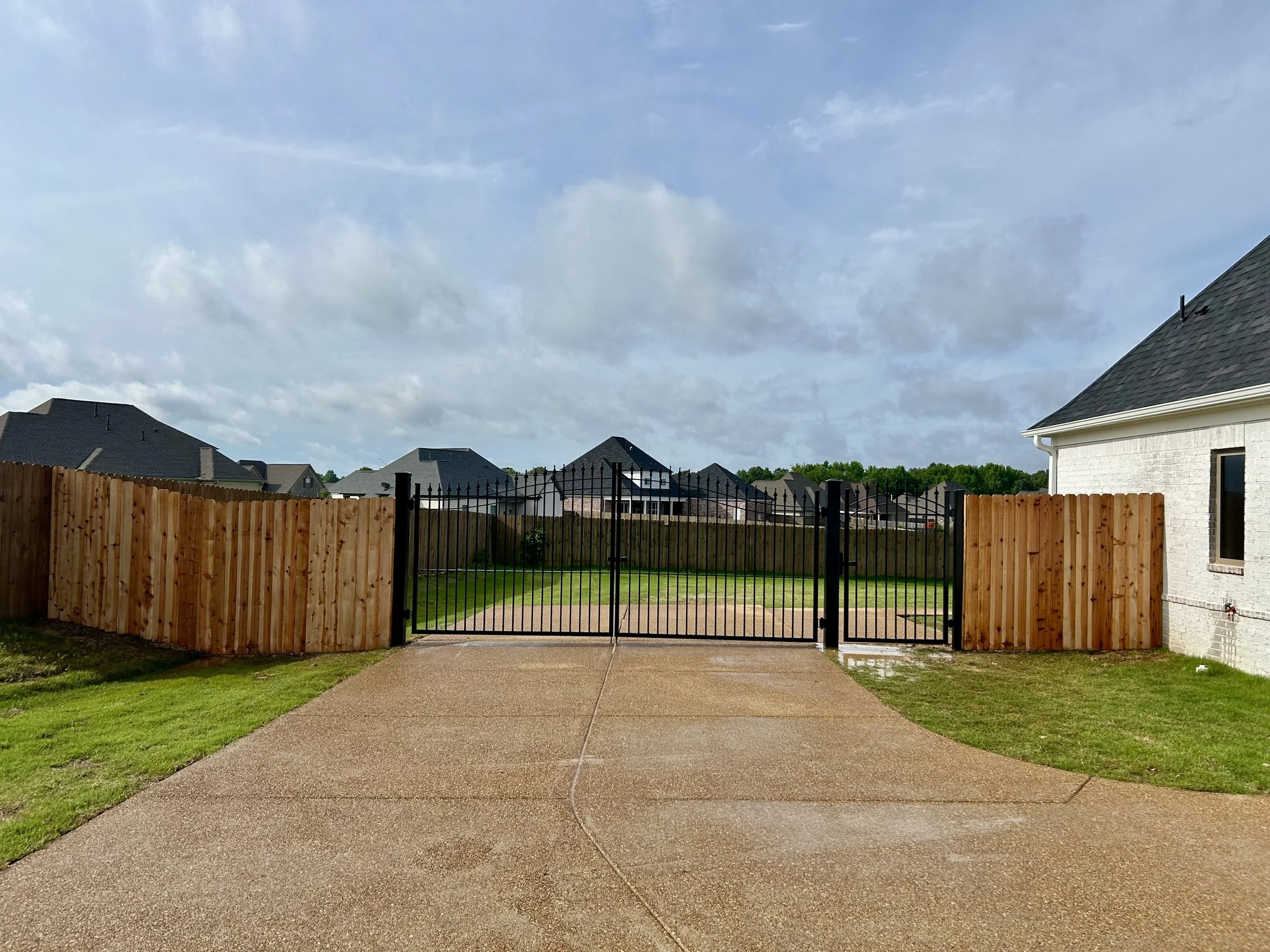 Double ornamental steel driveway gate with a matching walk gate and cedar privacy fence installed in Southaven, Mississippi by DeSoto Fence Co.