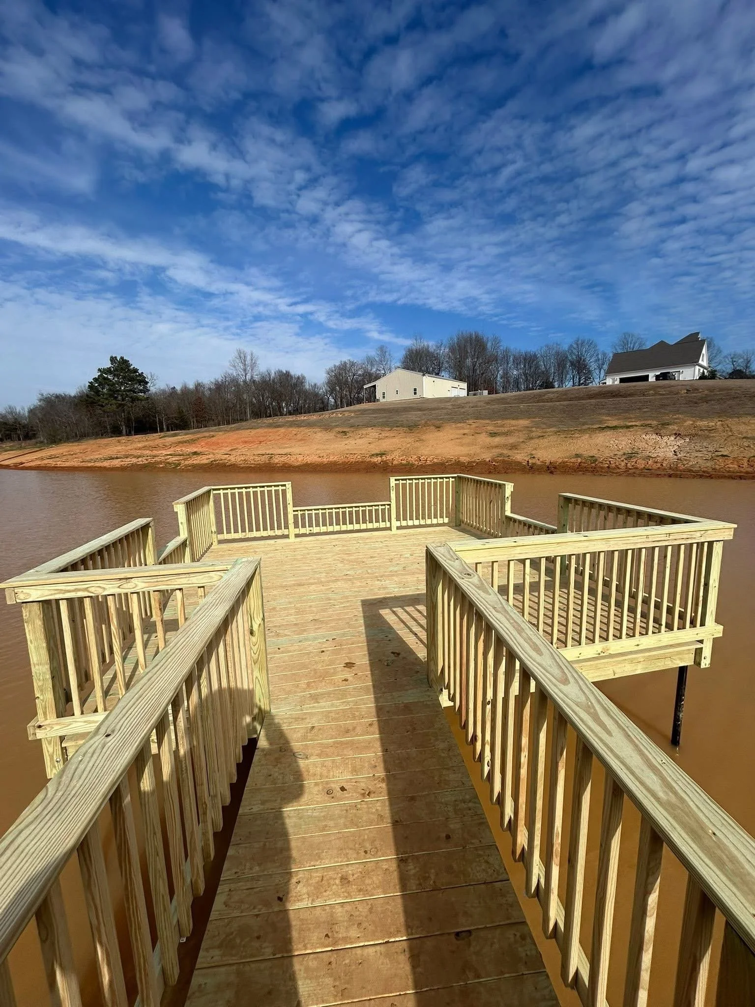 Custom Lake Dock in Nesbit, Mississippi by DeSoto Fence Co. featuring pressure treated lumber, elevated waterfront access, safety railings, and spacious dock design built for relaxation and outdoor enjoyment.