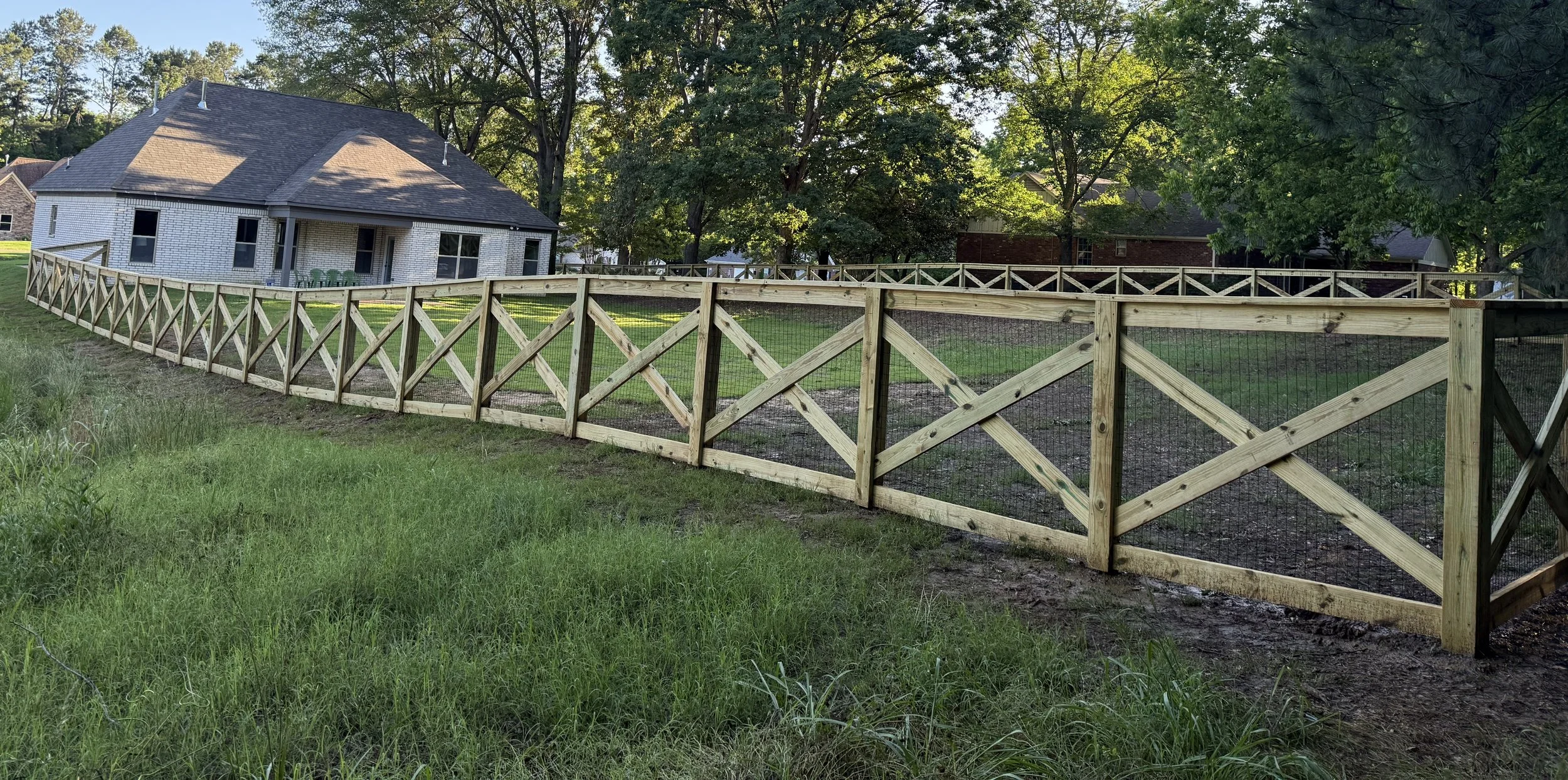 Full property view of a custom crossbuck fence with black wire in Olive Branch, MS. Designed to provide boundary control while maintaining an open and natural look.