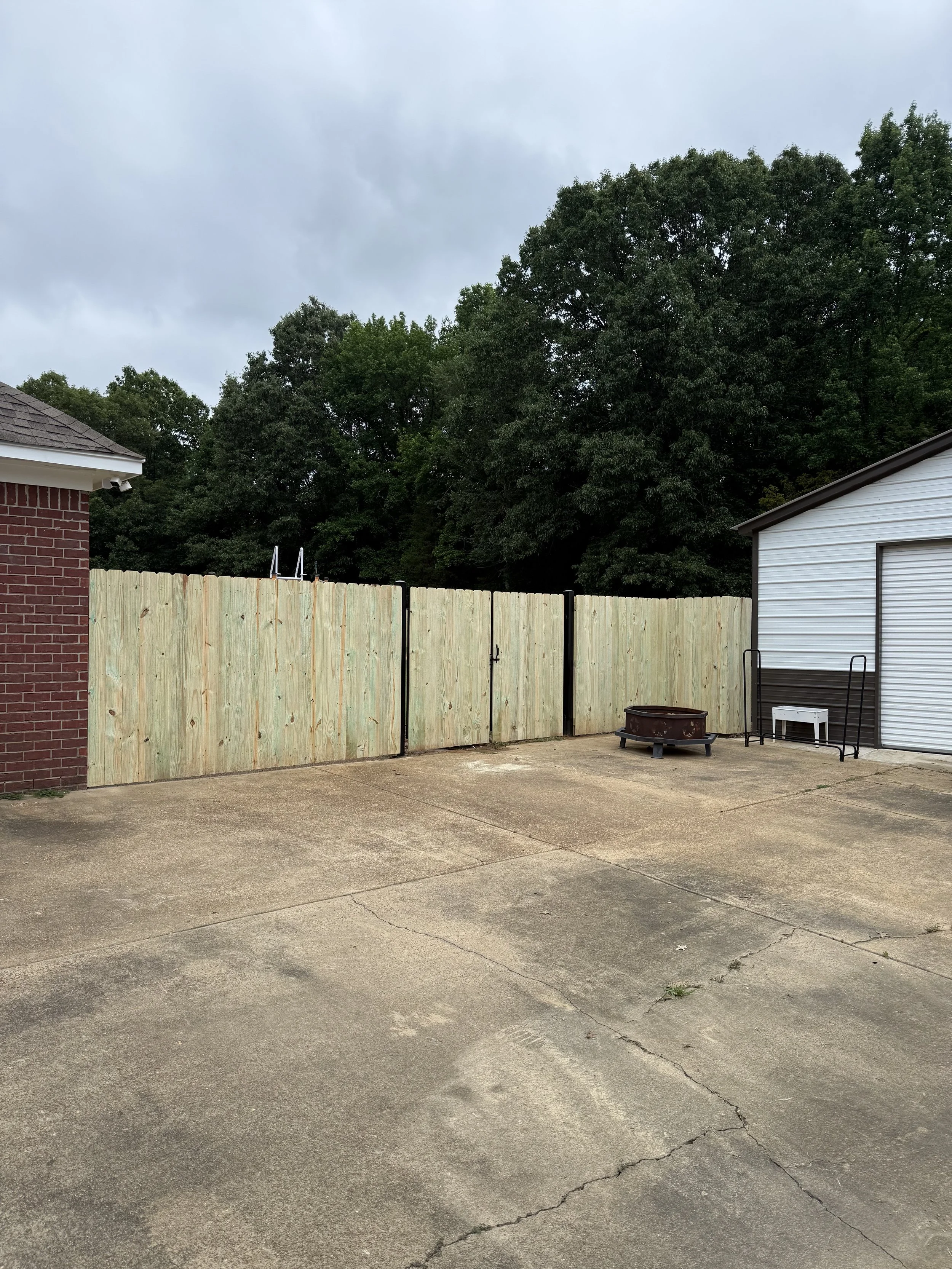 Custom steel-framed double pine driveway gate installed with a pine privacy fence in Hernando, Mississippi.