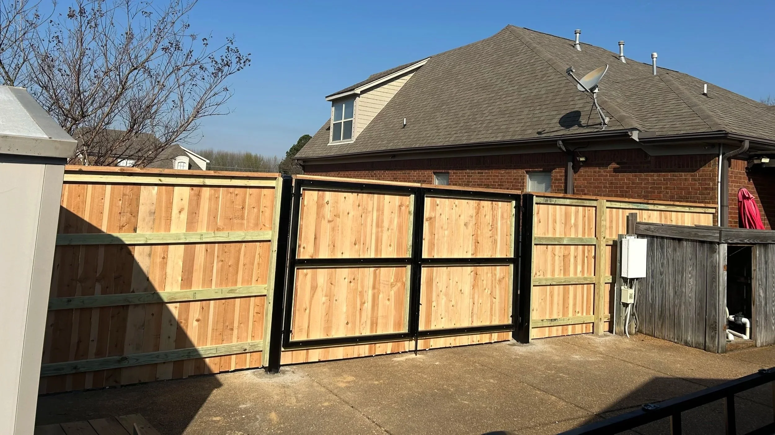 Custom double cedar driveway gate with welded steel frames installed as part of a residential privacy fence in Hernando, Mississippi by DeSoto Fence Co.