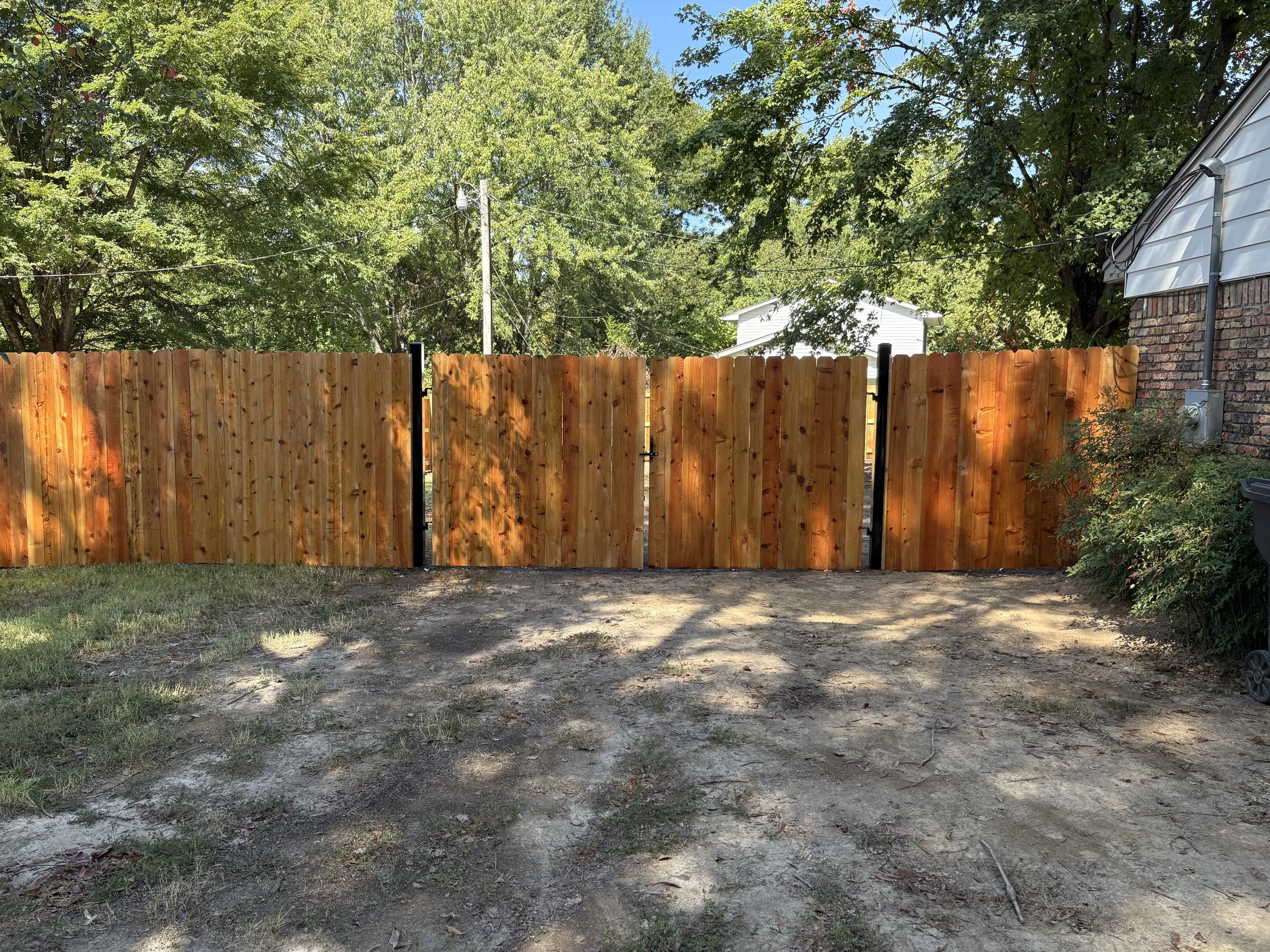 Custom double cedar driveway gate with welded steel frames installed as part of a residential privacy fence in Hernando, Mississippi by DeSoto Fence Co.  Hernando Fence Company Wood Fences Fence Styles Gallery Steel Frame Gates section