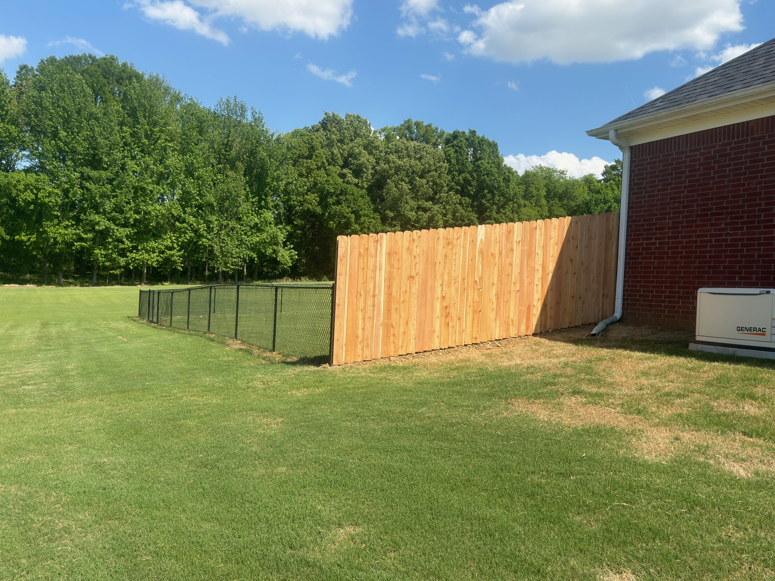 Black chain link fence with cedar privacy sides installed in Hernando, MS by DeSoto Fence Co.