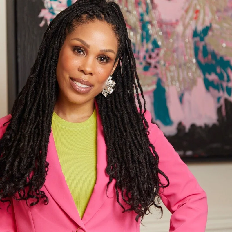 Picture of a Black woman with long locs wearing a lime green sweater and bright pink blazer