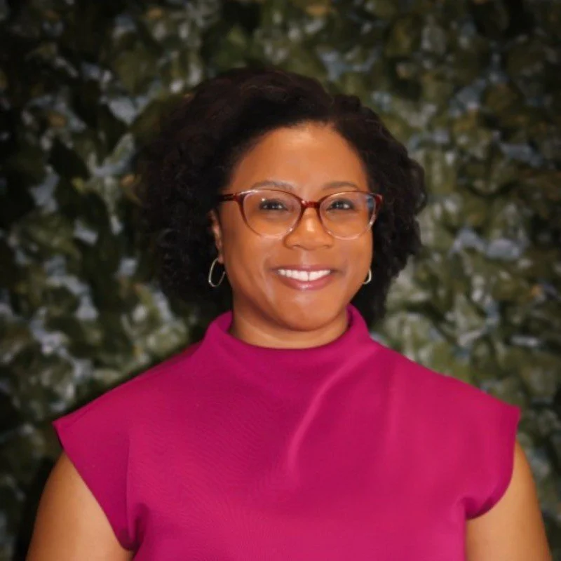 Picture of a Black woman wearing glasses and a pink turtleneck