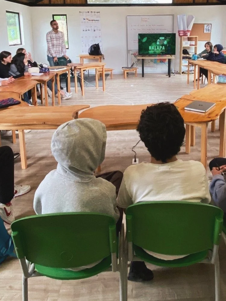 Personas en un aula viendo una presentación en la televisión.