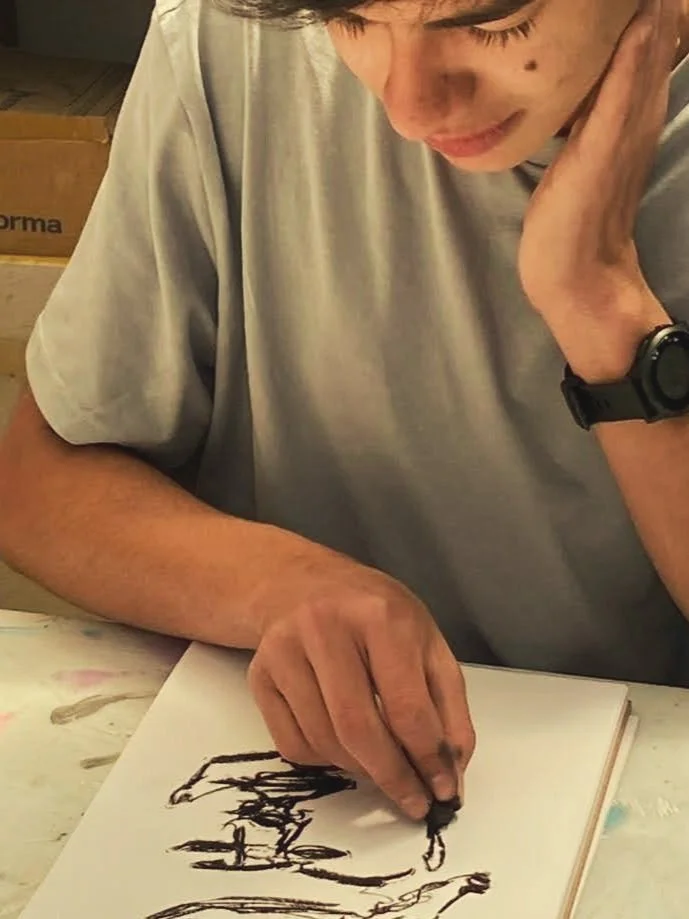 Persona dibujando en un bloc de notas con carboncillo.