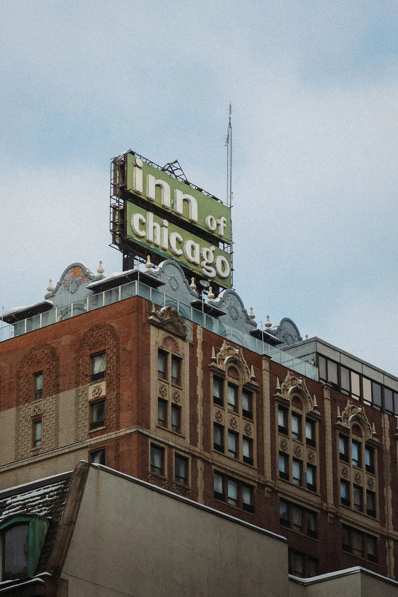The historic Hotel of Chicago building with a large sign on top that reads 'Inn of Chicago' in vintage lettering, with a blue sky background.
