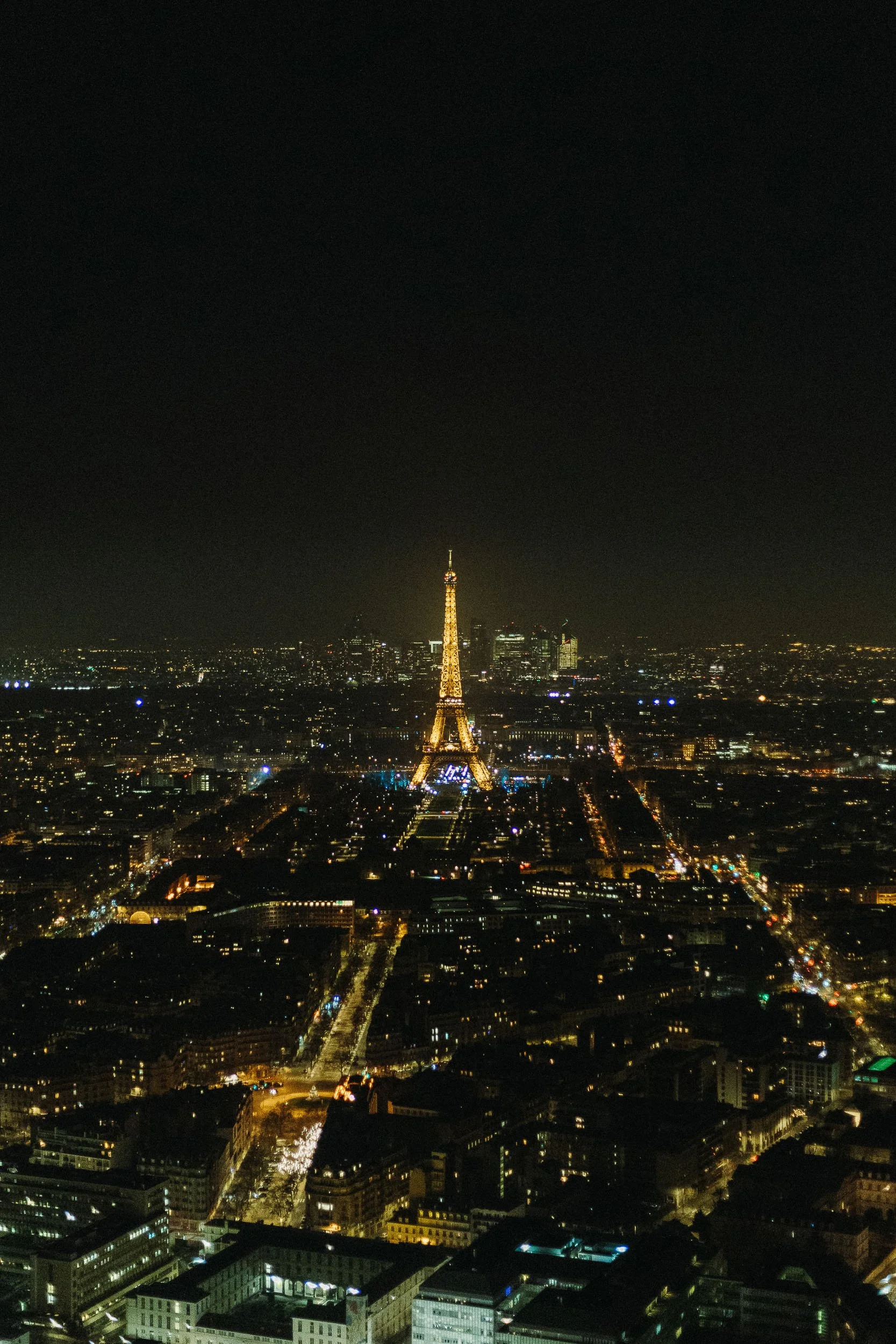Night view of Paris with illuminated Eiffel Tower and city lights.