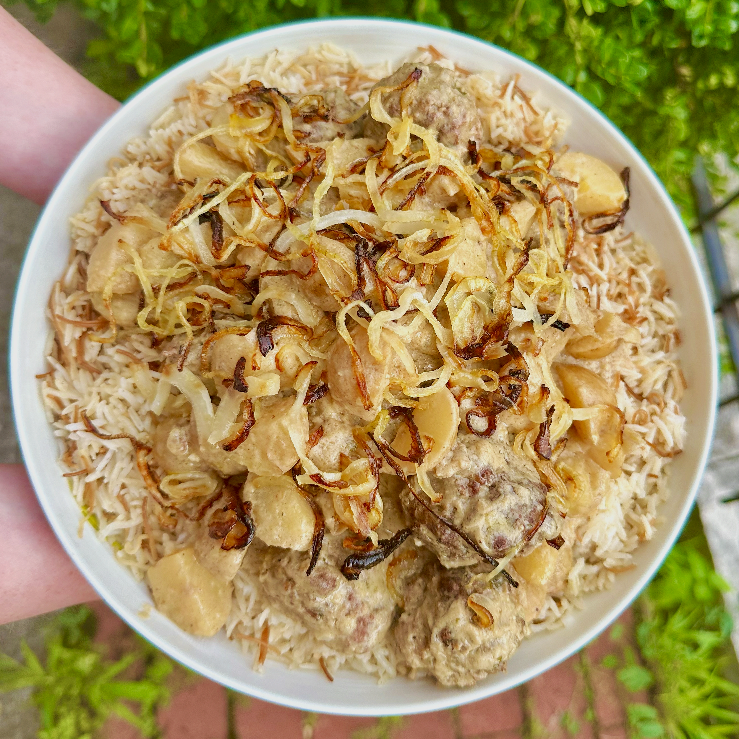 A bowl of Vermicelli Rice, topped with meatballs, potatoes, and crispy onions