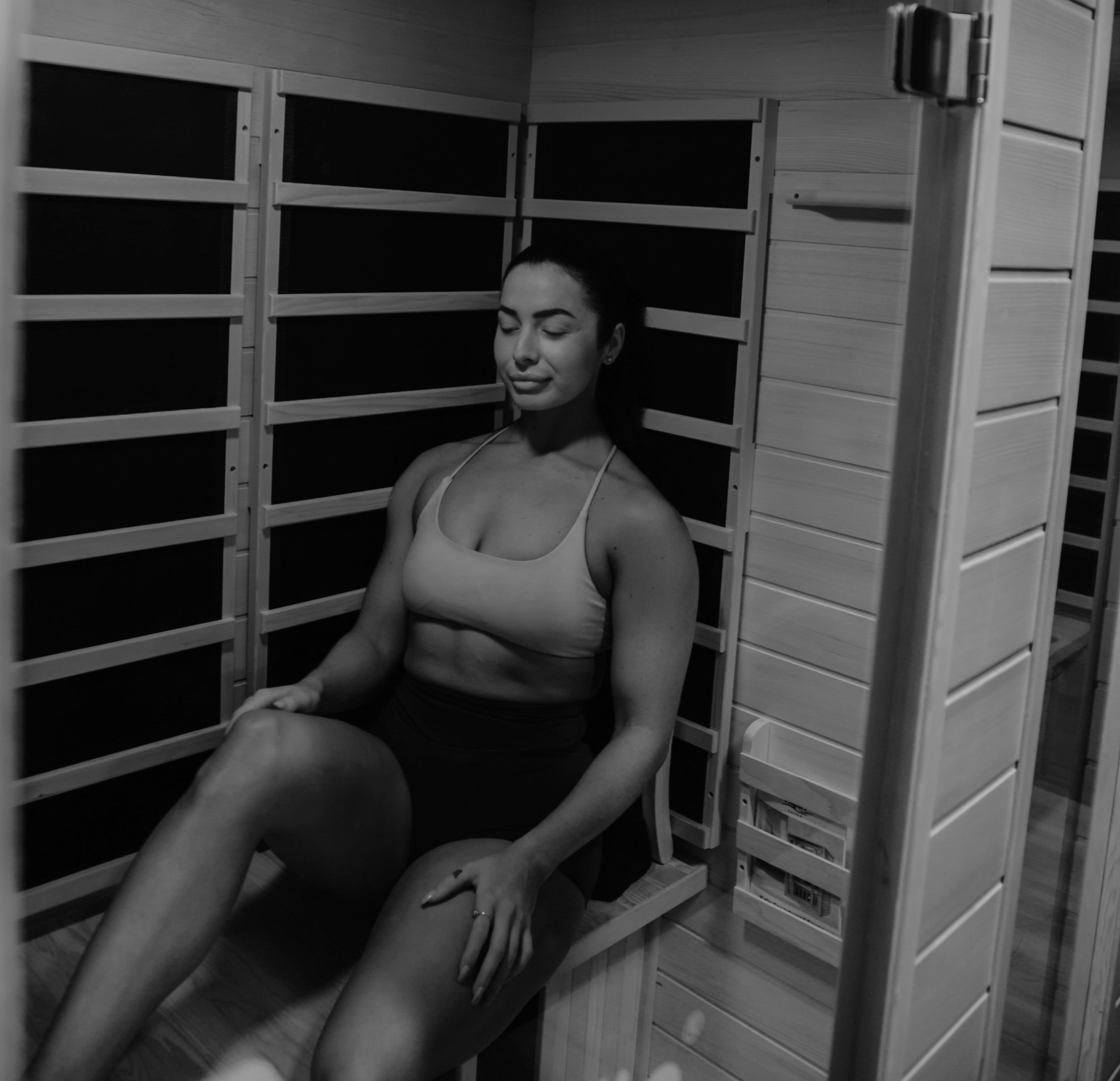 A woman sitting with her eyes closed inside a room with wooden shelving units surrounding her.