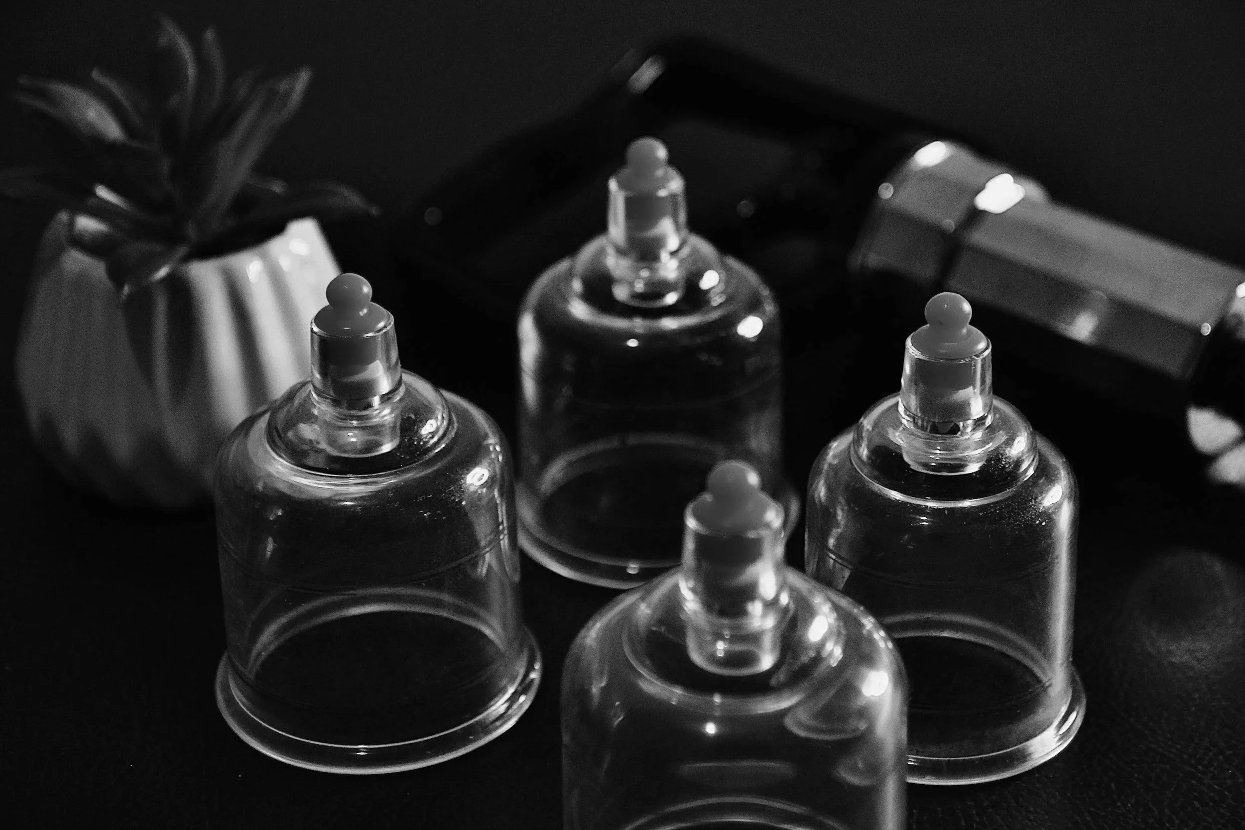 A close-up of several empty plastic squeeze bottles with pointed nozzles on a dark surface.