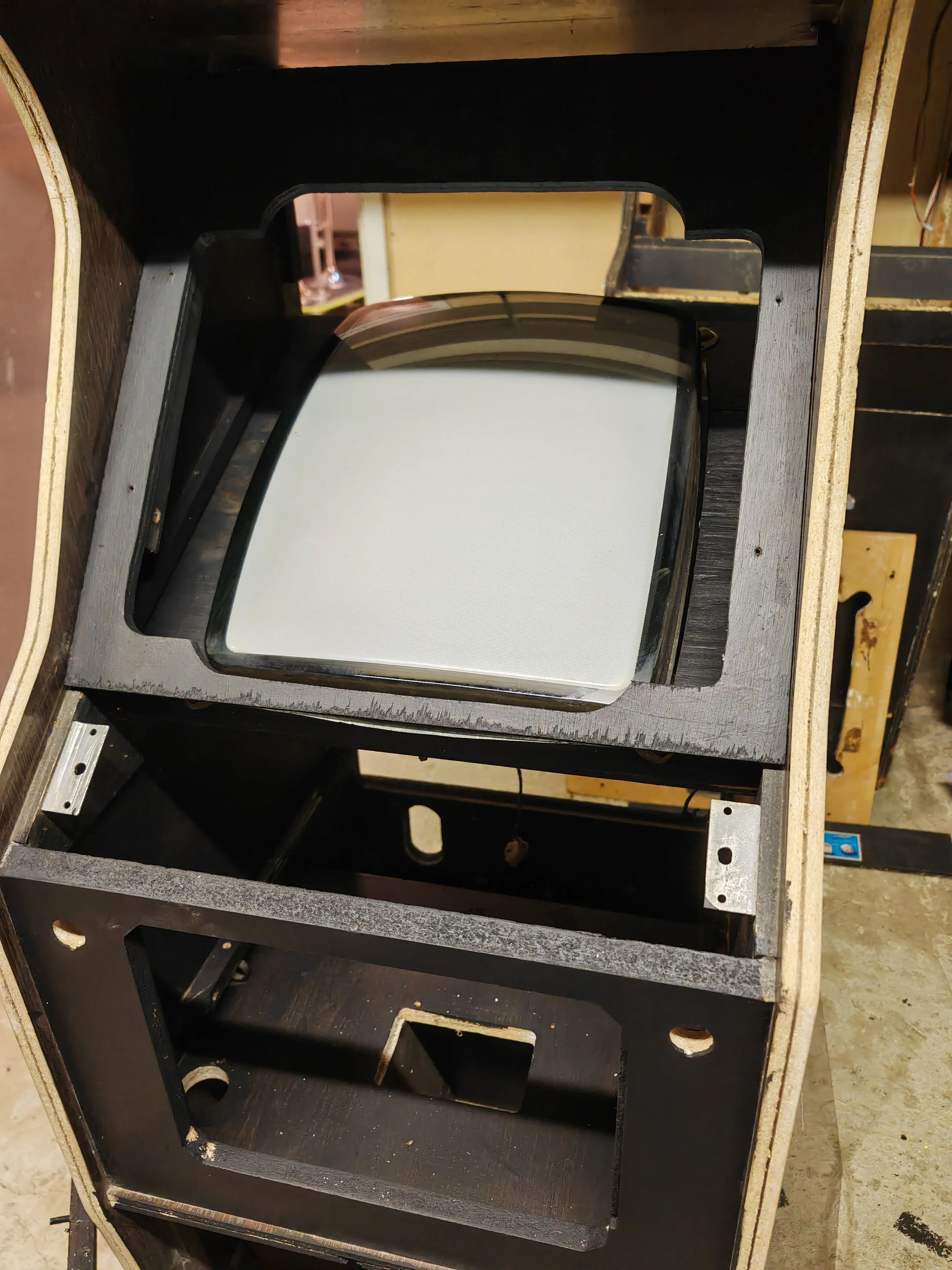 A vintage wooden arcade cabinet with an empty space for a screen and a mounted internal monitor.