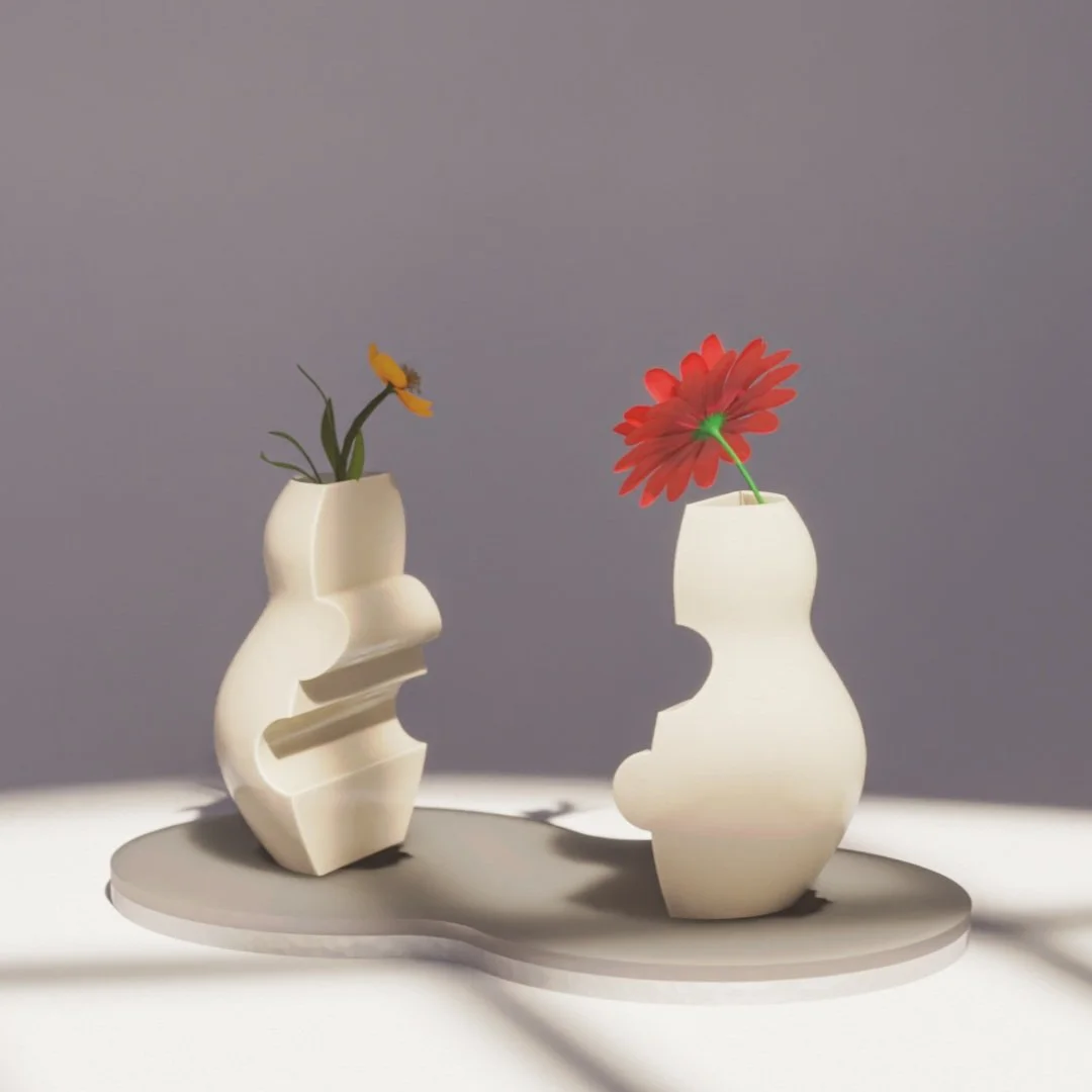 Two abstract white vases with flowers on a gray irregularly shaped tray against a gray background