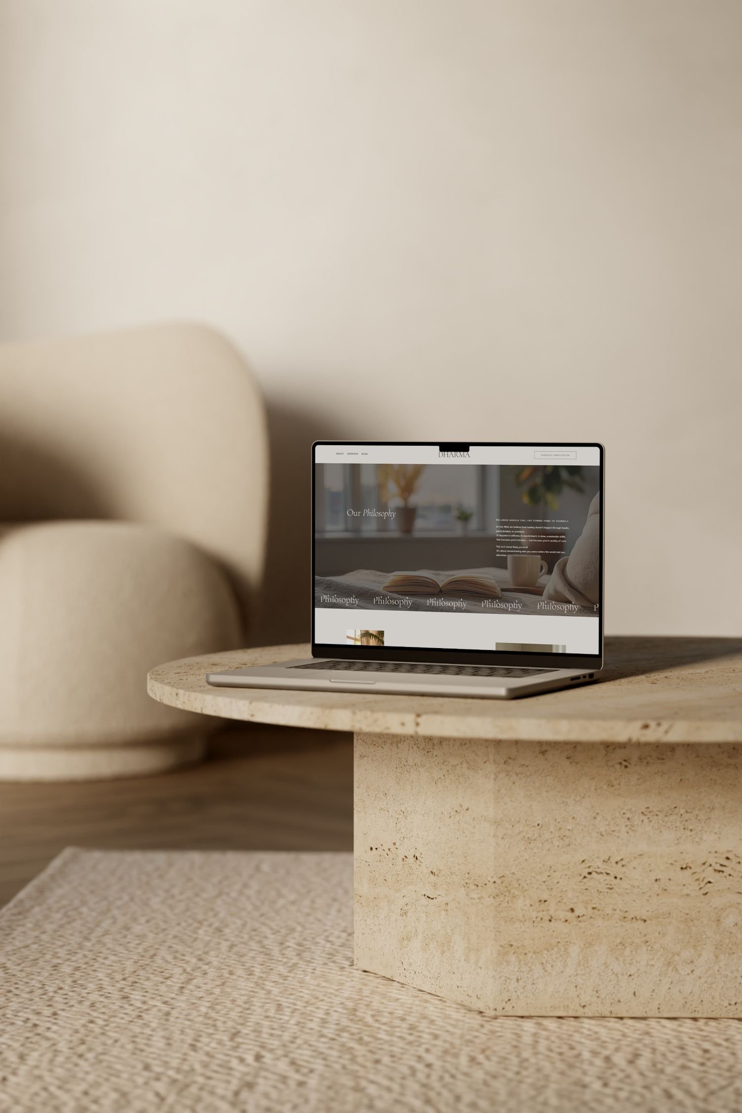A laptop sitting on a light-colored textured coffee table in a cozy, modern living room with a beige sofa and a white wall.