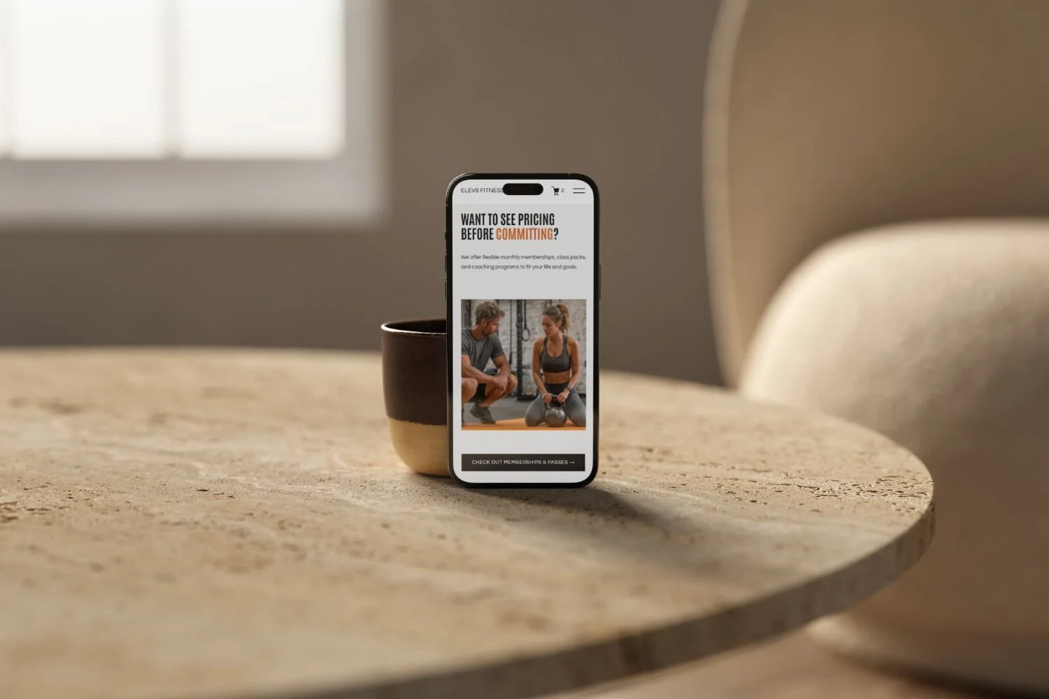 Smartphone on a wooden table displaying Elevate, a fitness gym website designed by Bohora.