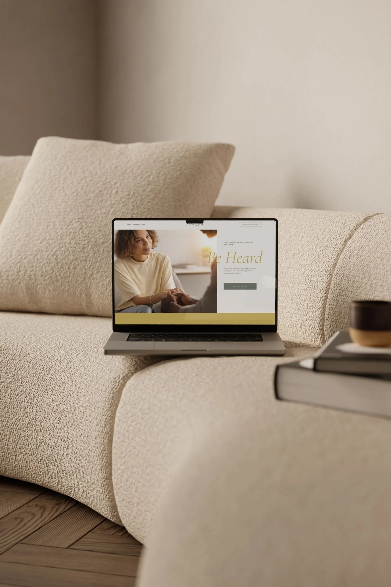 A laptop on a beige sofa displaying Dharma website designed for therapists and psychologists by Estudio Bohora.