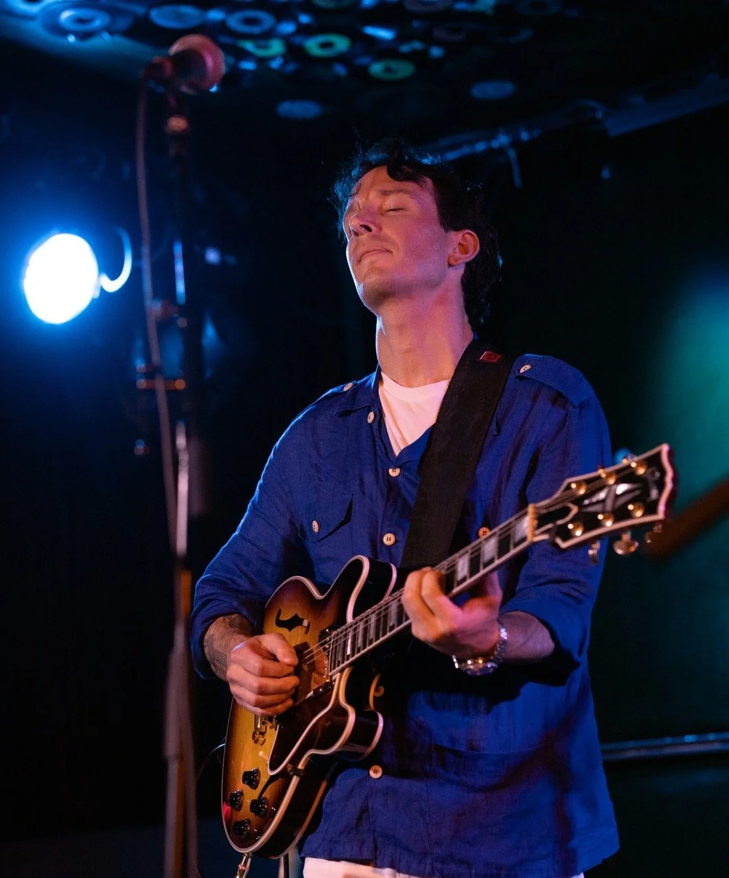 Guitarist standing onstage playing guitar.