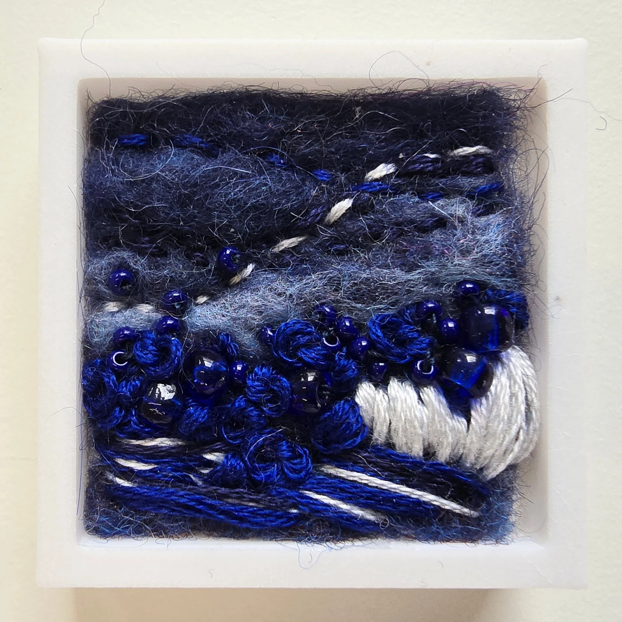 Mini 9 | Needle felted wool, glass beads, & stitching in a white composite frame | 1.75" x 1.75" x 0.5" | $30 (CDN) ***Available at Tiny Ass Art Gallery, St. Jacobs, Ontario in May 2026