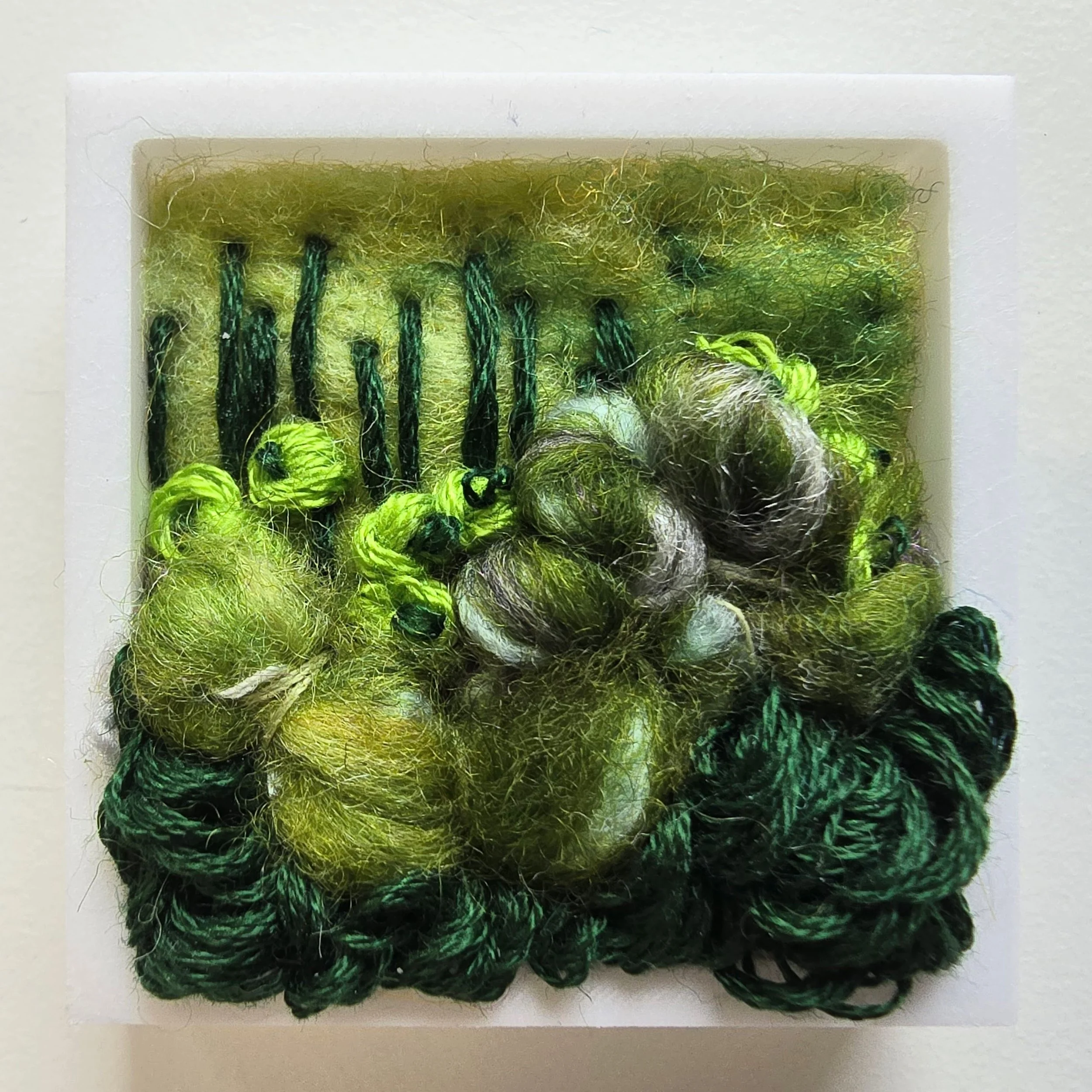 Mini 1 | Needle felted wool, handspun art yarn, mixed yarns, & stitching in a white composite frame | 1.75" x 1.75" x 0.5" | $30 (CDN) ***Available at Tiny Ass Art Gallery, St. Jacobs, Ontario in May 2026