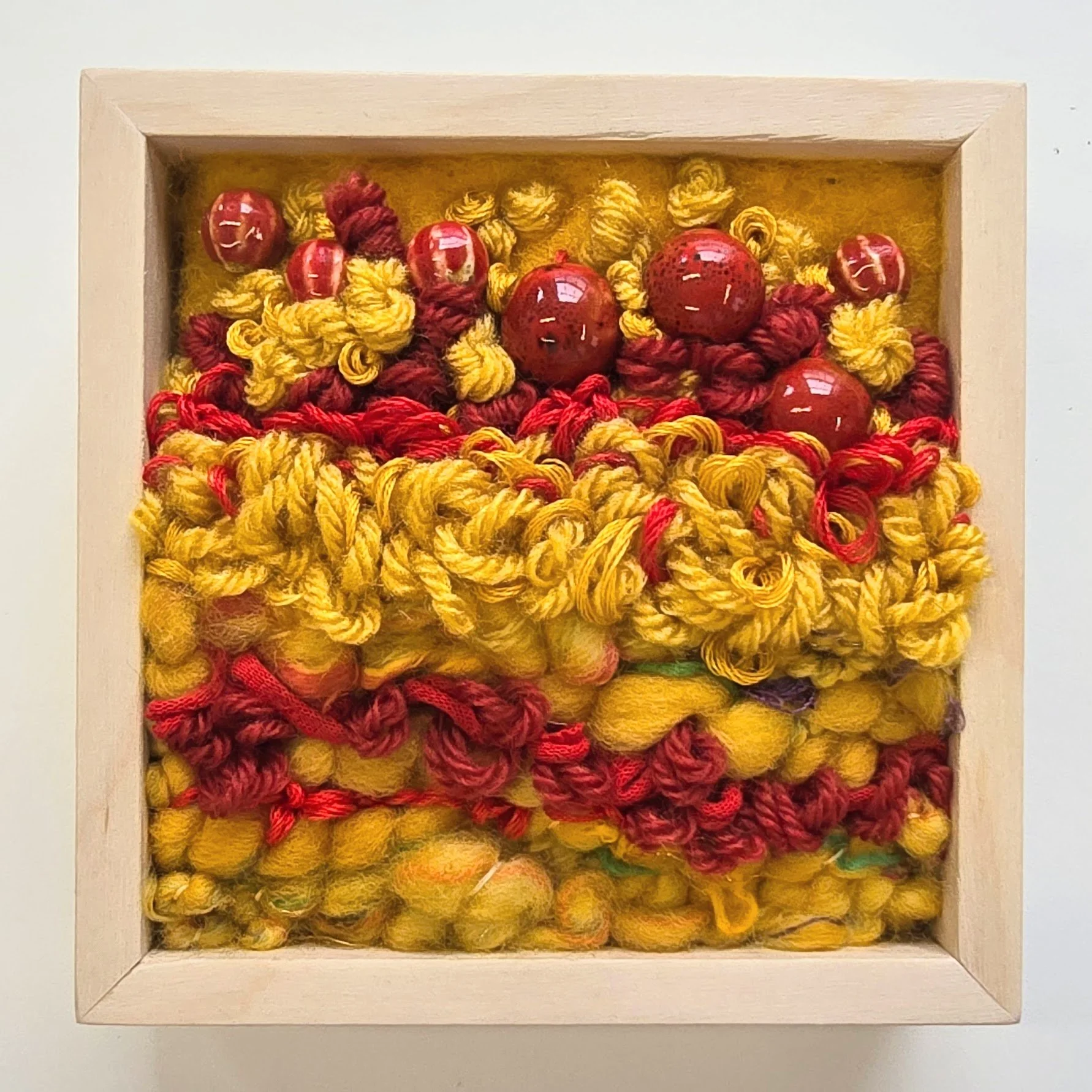 Apple of My Eye | Needle felted wool, handspun art yarn, mixed yarns, stitching, & ceramic beads in a solid birch frame with natural finish | 5" x 5" x 2" | $125 (CDN) ***Available at Tiny Ass Art Gallery, St. Jacobs, Ontario in May 2026