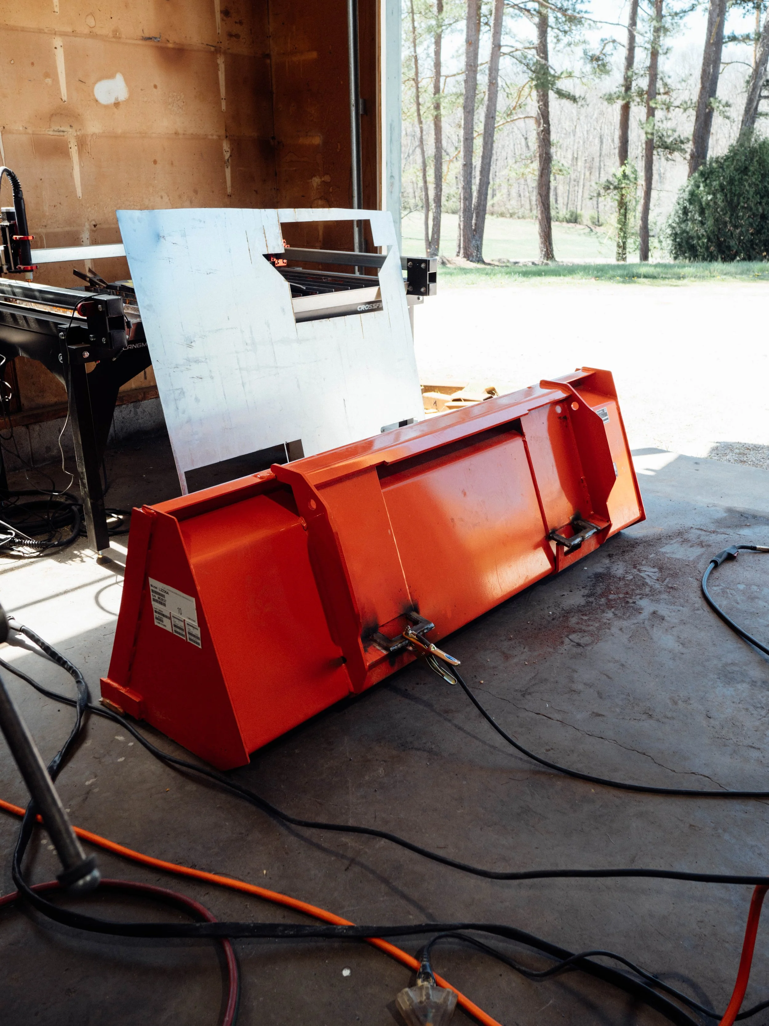 Tractor bucket in fabrication shop during repair process in London KY showing equipment welding setup