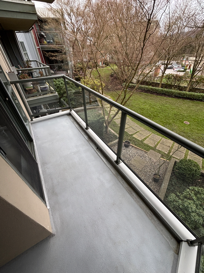 View from a balcony overlooking a grassy yard with a stone pathway and leafless trees during daytime.