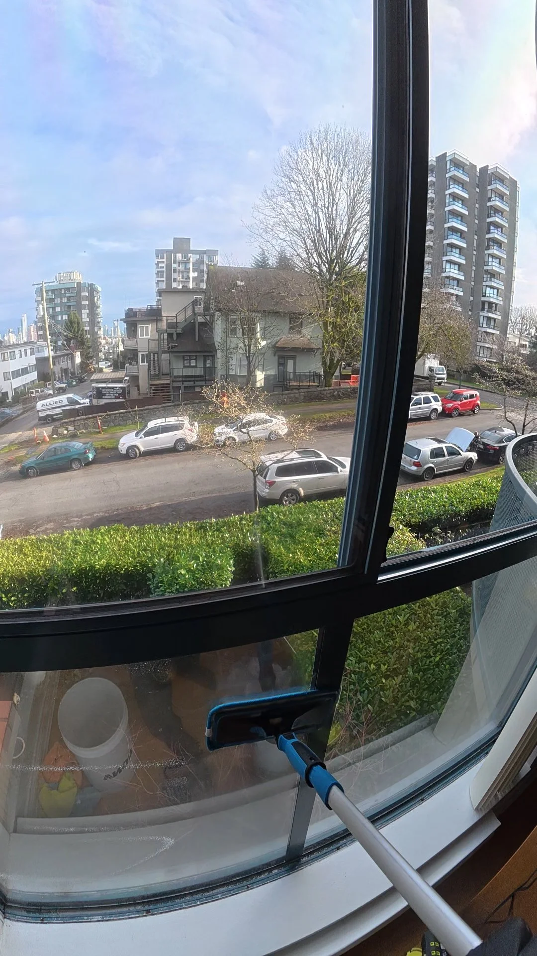 Modern building with wooden facade and large glass window in a mountain landscape with hills and sparse vegetation.