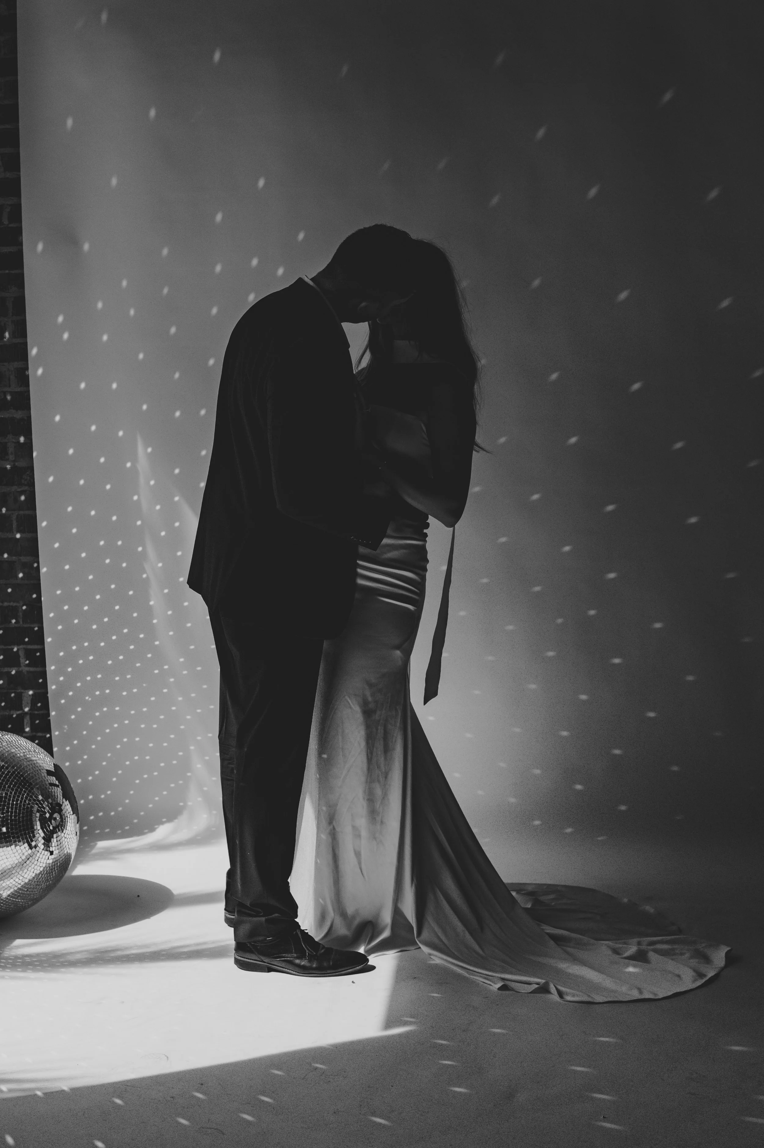 Silhouette of a couple embracing on the dance floor, with a soft light effect and disco ball reflections creating a romantic atmosphere.