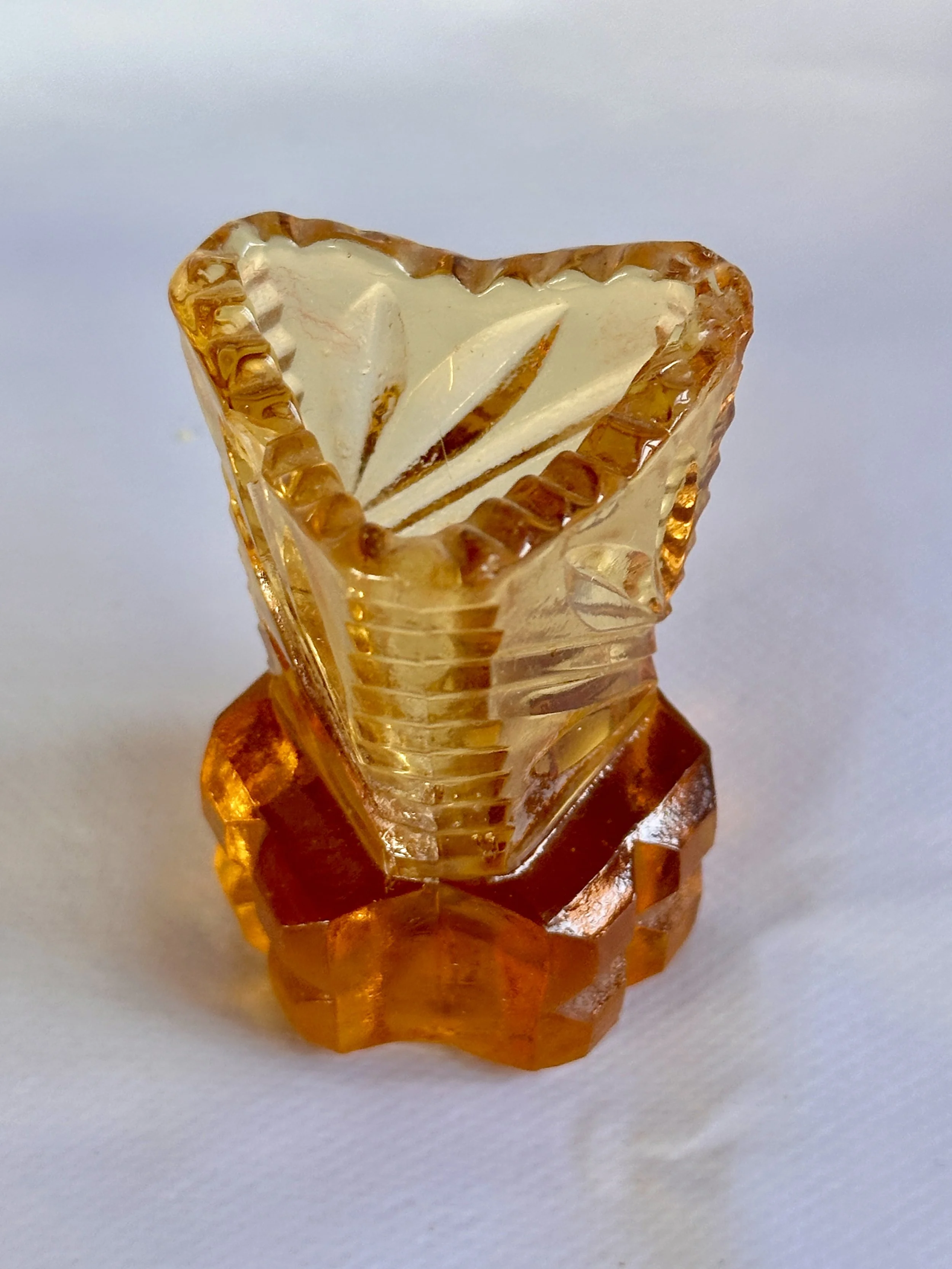 Close-up of a small, decorative amber-colored glass item with intricate design, set against a plain white background. Available in the Curated by Curtis online Vintage Store. 