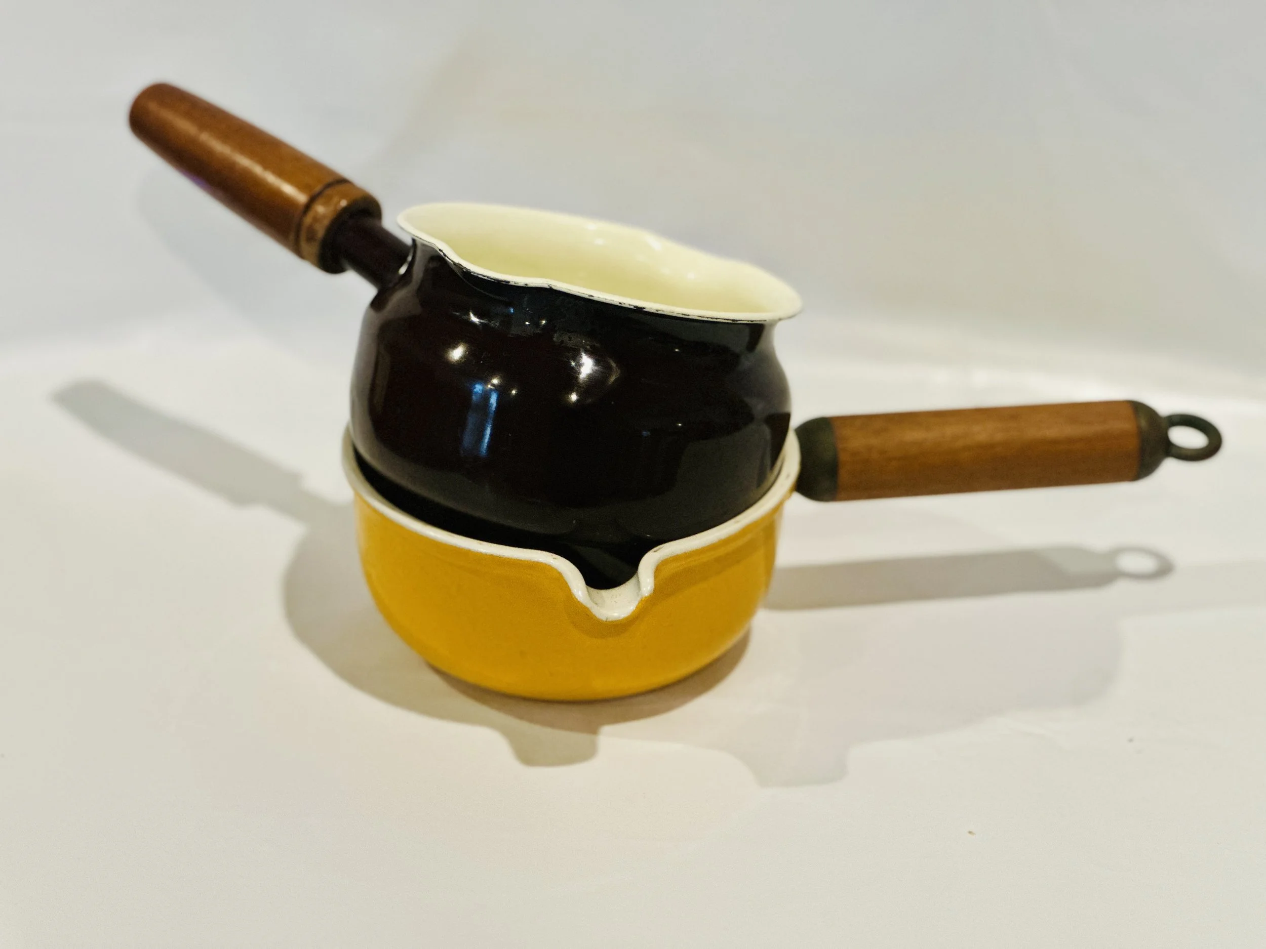 A small, vintage-style black and yellow ceramic coffee pot with a wooden handle and lid, placed on a white surface against a plain white background. Available in the Curated by Curtis online Vintage Store. 