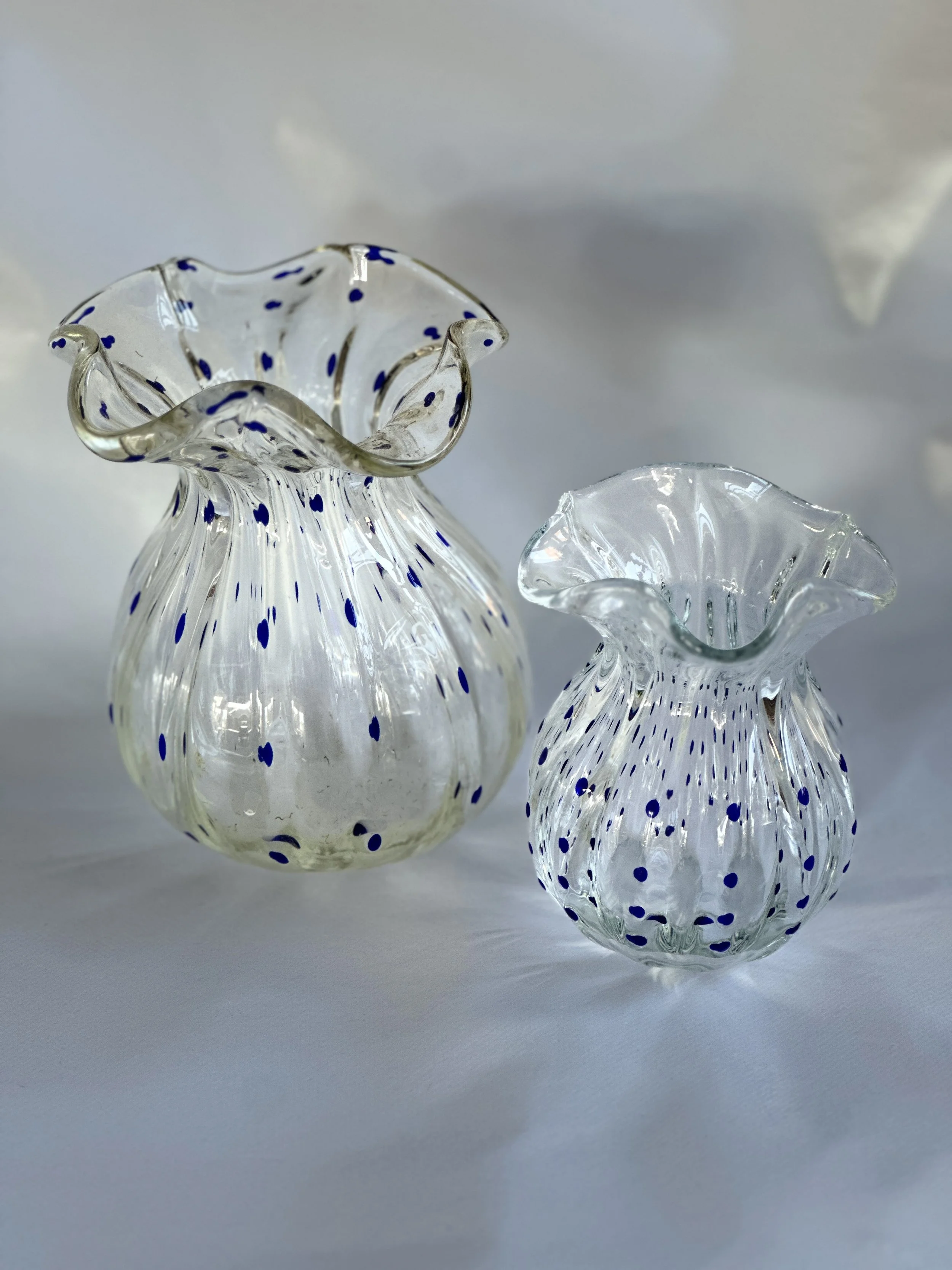 Two clear glass vases with blue dots, one larger and one smaller, placed on a white surface. Available in the Curated by Curtis online Vintage Store. 
