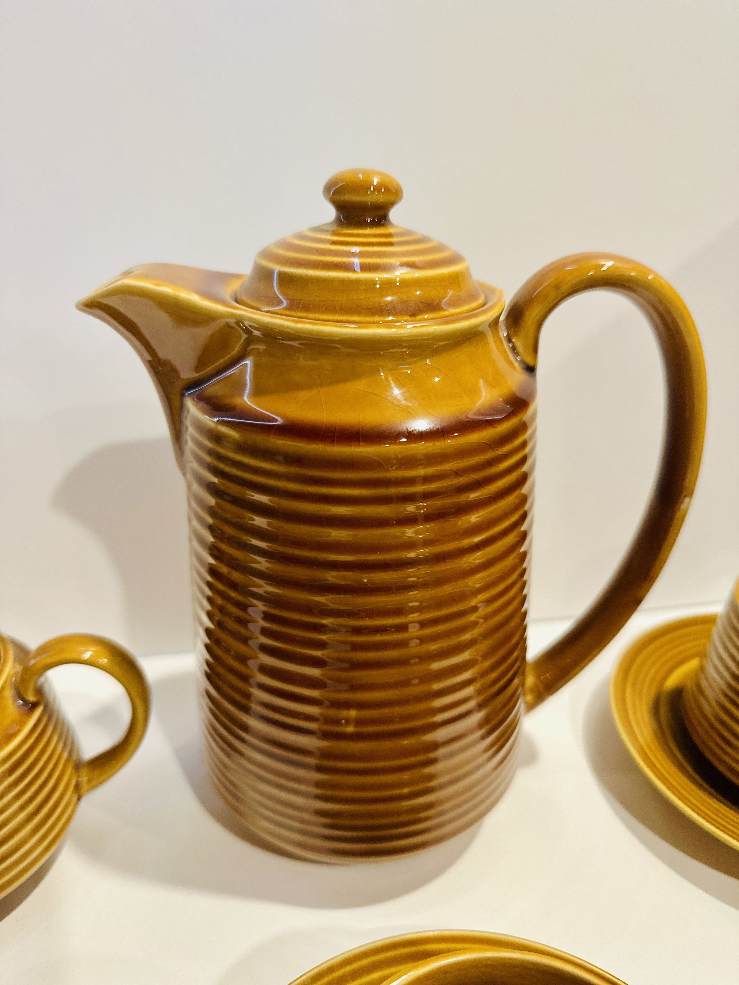 A ceramic teapot with a glossy, amber-colored glaze, featuring a ribbed texture and a rounded lid. Available in the Curated by Curtis online Vintage Store. 