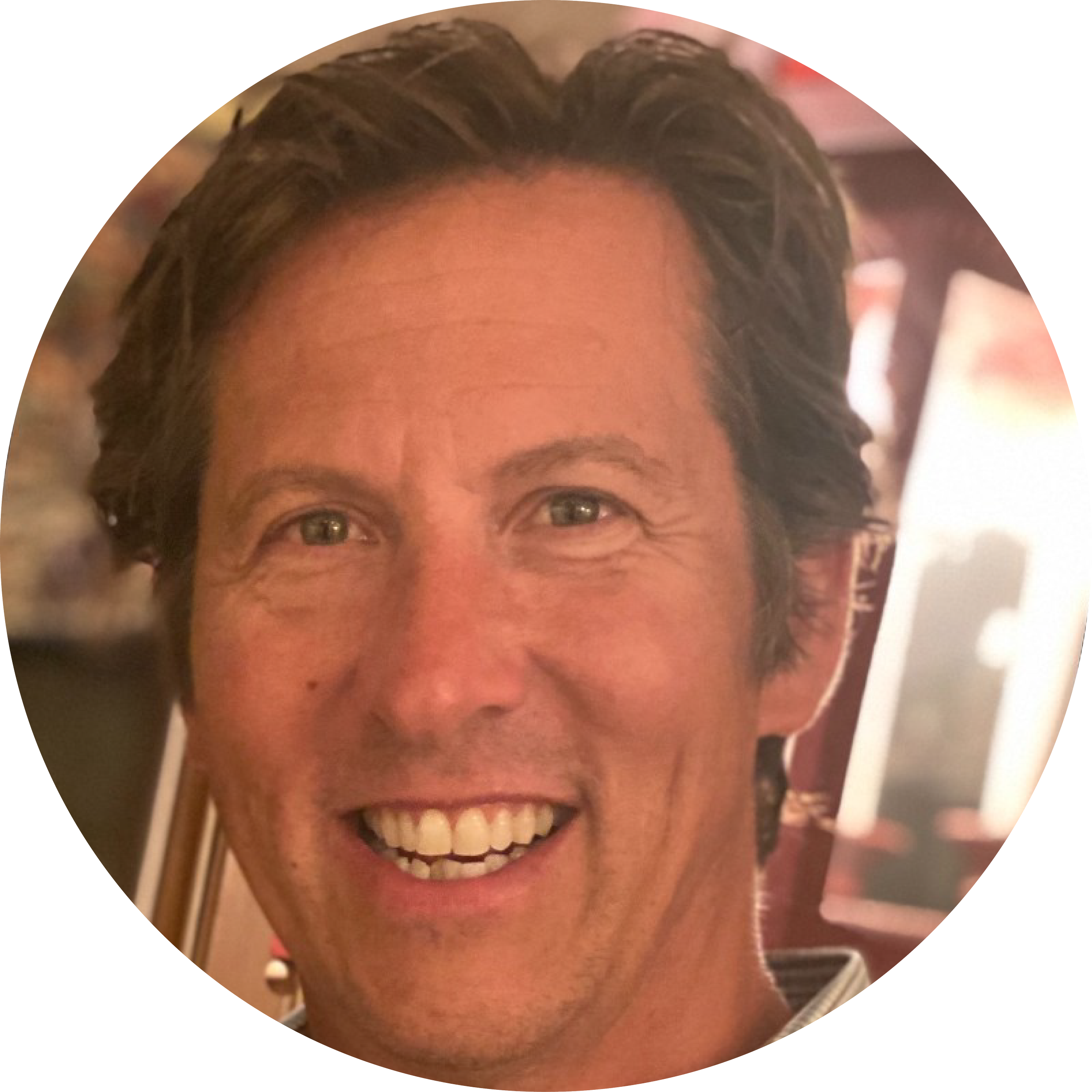 Smiling man indoors with blurred background.