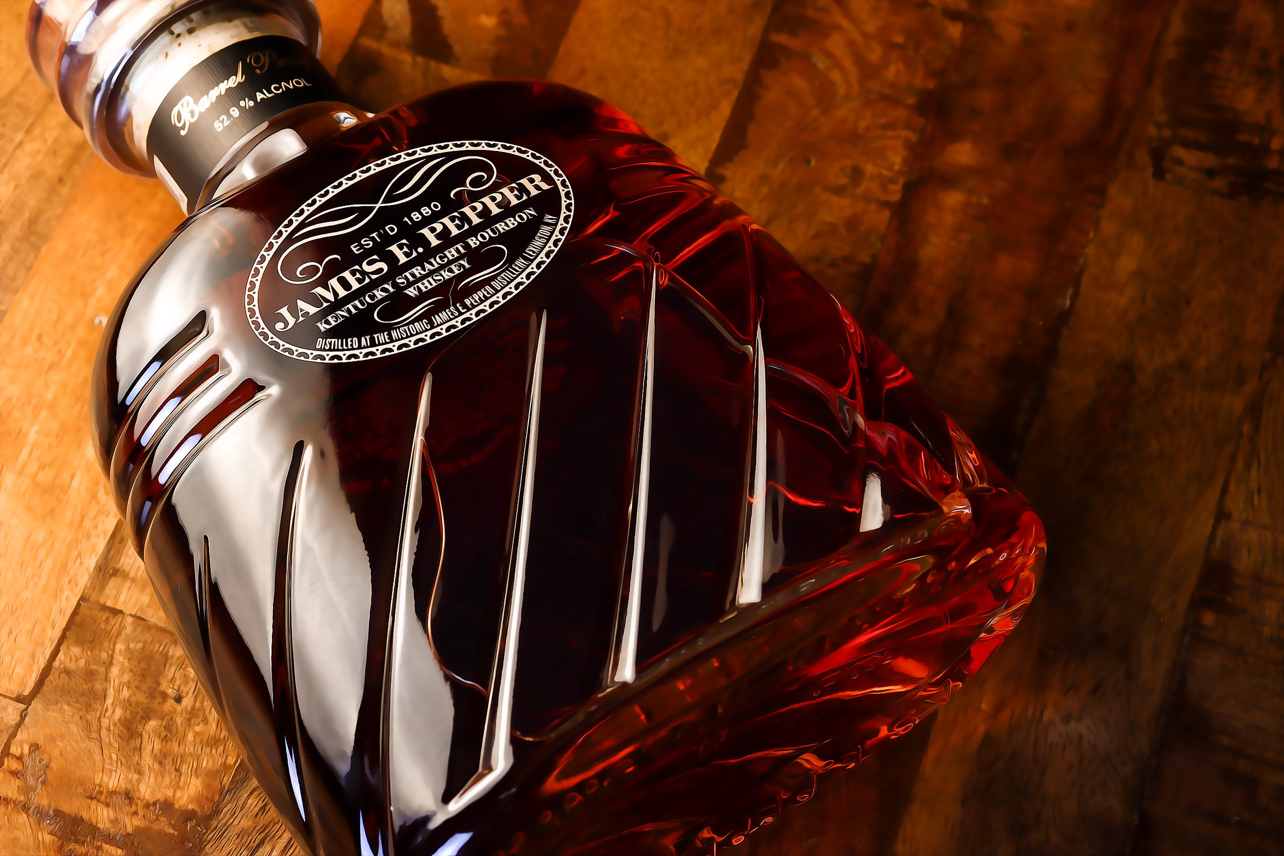 A bottle of James E. Pepper Kentucky Straight Bourbon Whiskey lying on its side on a wooden surface.