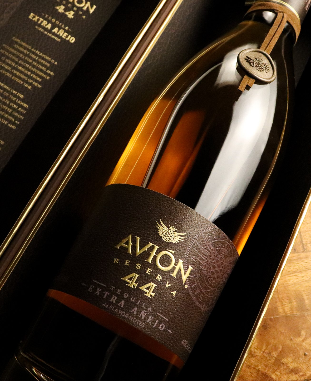 A bottle of Avión Reserva 44 tequila in its box, with a black and gold label and decorative seal on the neck.