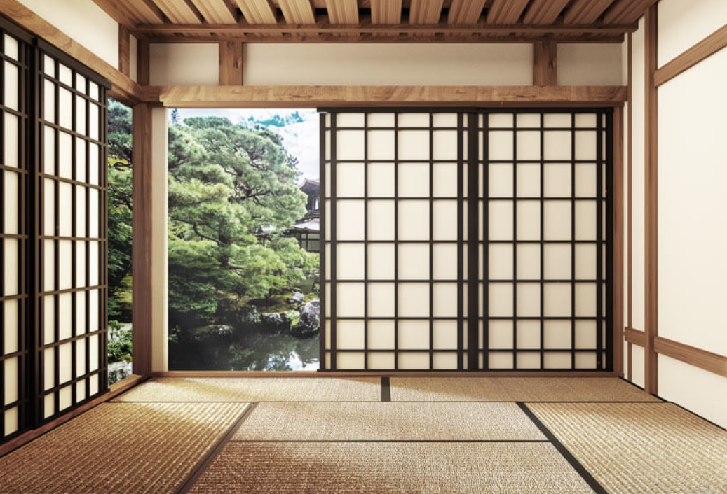 Traditional Japanese room with shoji sliding doors and tatami mats, overlooking a garden with trees and rocks.