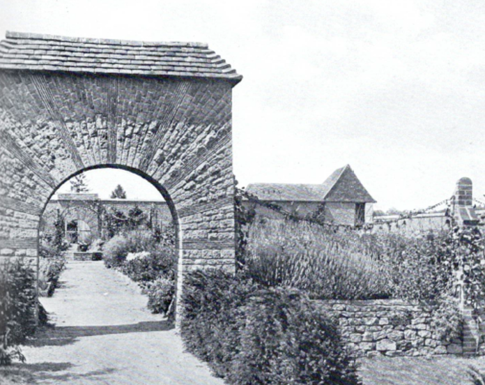 Original Arts & Crafts era stone archway designed by the great designer Thomas Mawson with tiled roof in black and white photo.