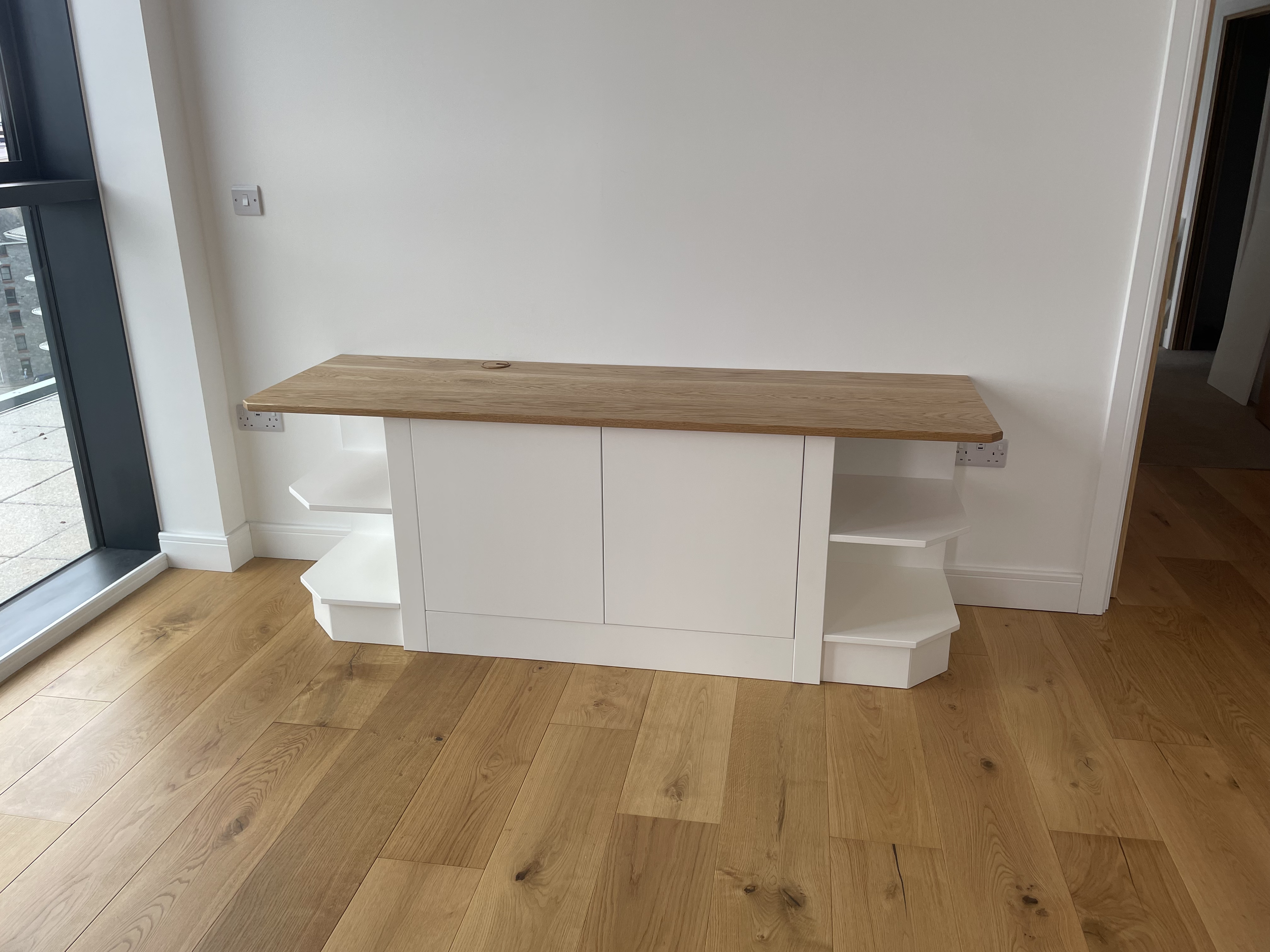 Empty room with wooden floors, white wall unit, and wooden countertop