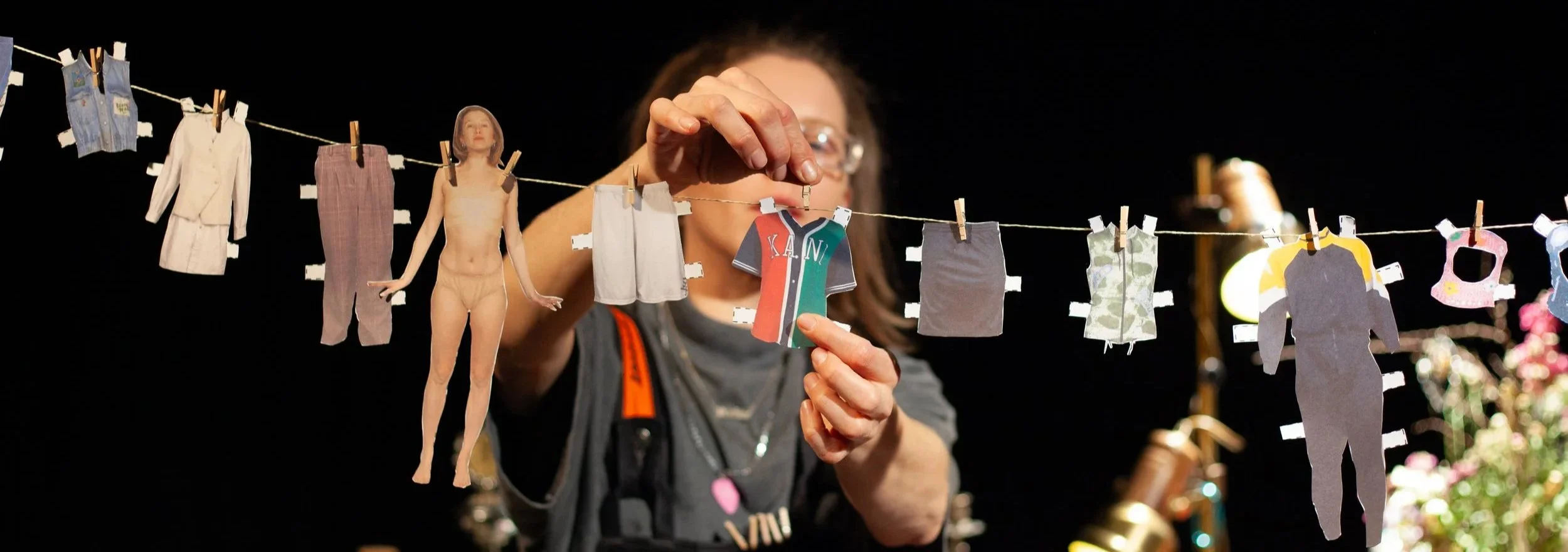 Bush.Ida hängt aus Papier ausgeschnitte Kleidungsstücke an eine kleine Wäscheleine.