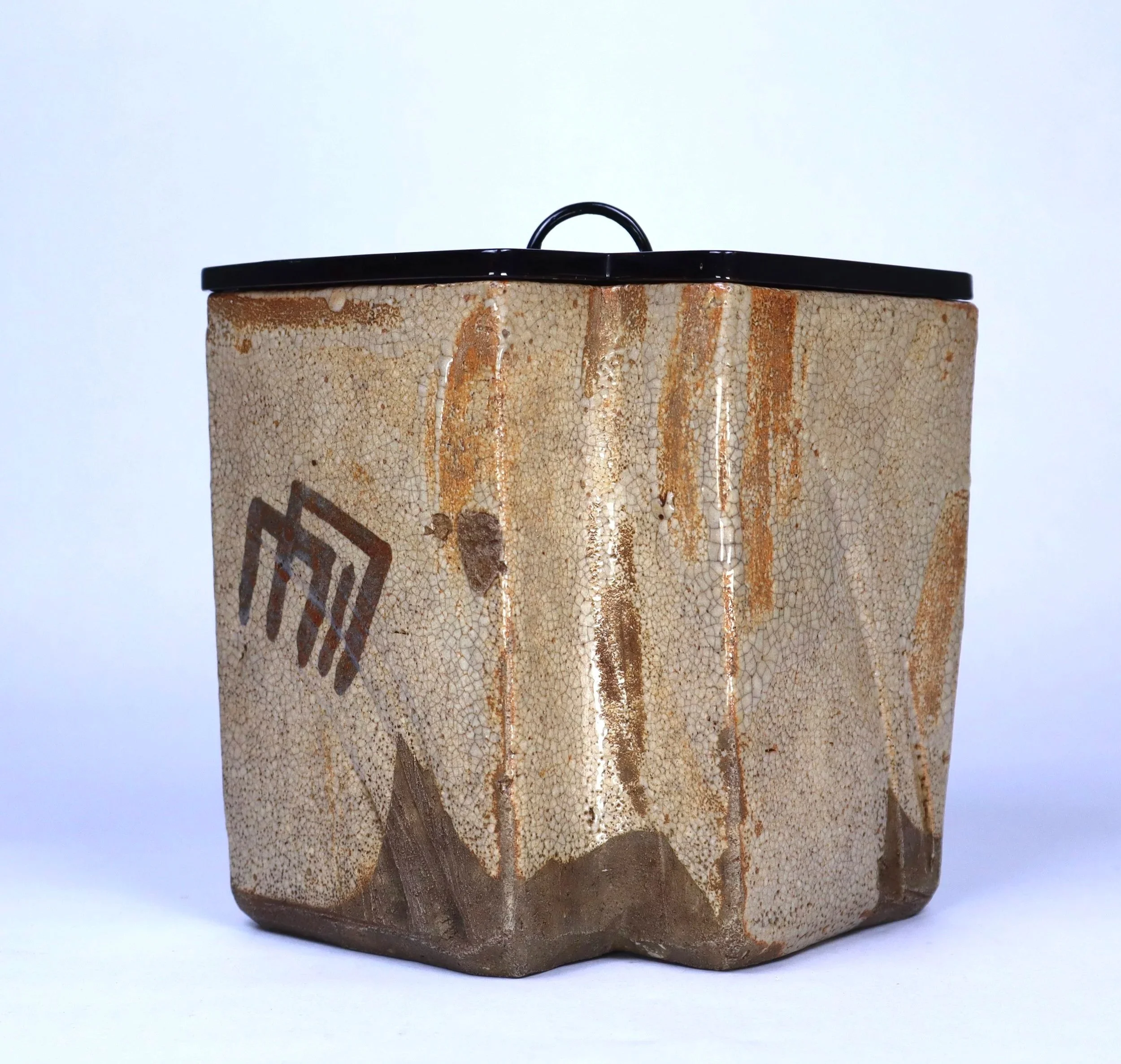 A ceramic box with a black lid, decorated with a desert landscape scene, including mountains and cacti, against a plain white background.