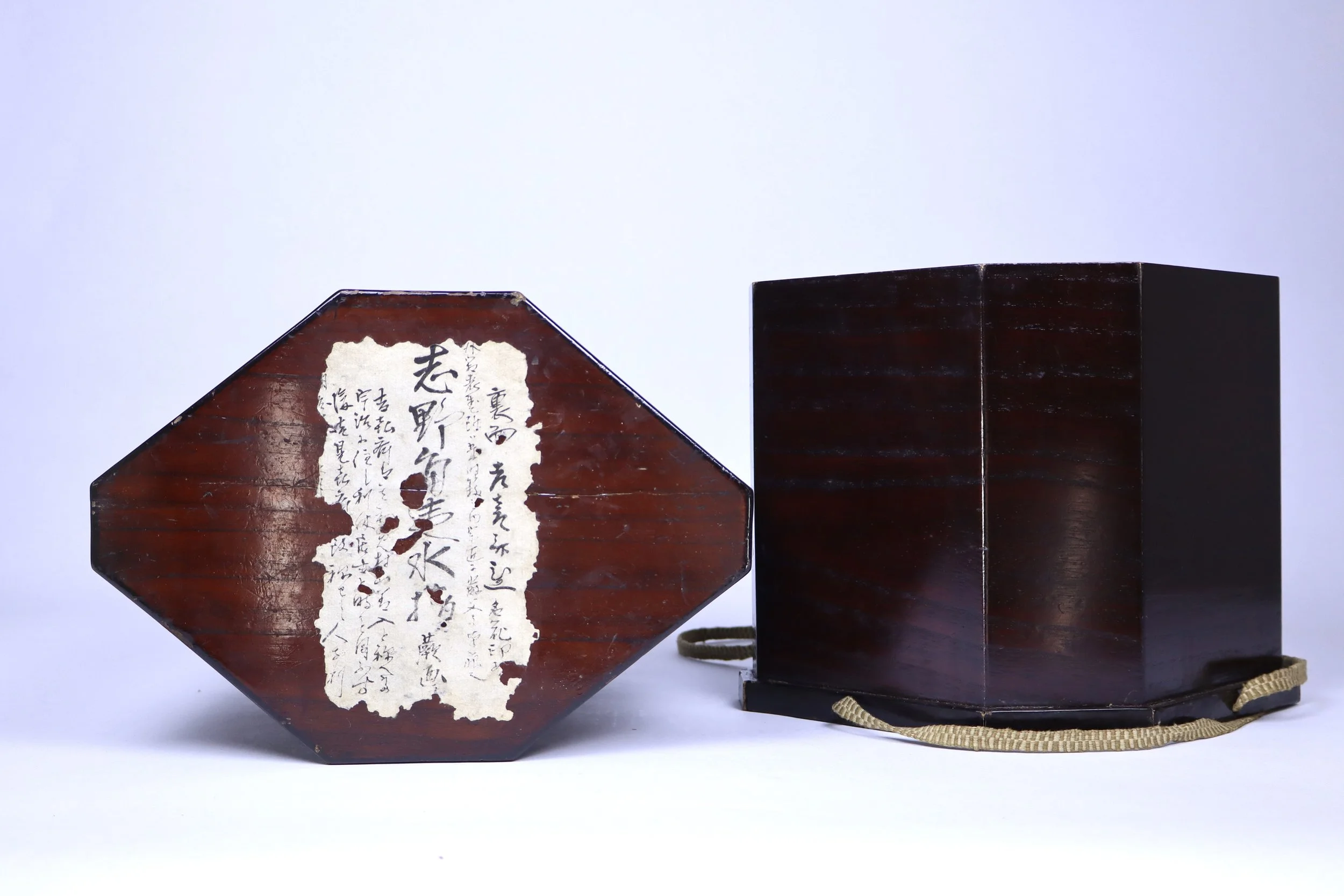 A traditional Japanese wooden box with a hexagonal lid and a carrying strap, featuring a paper label with Japanese calligraphy.