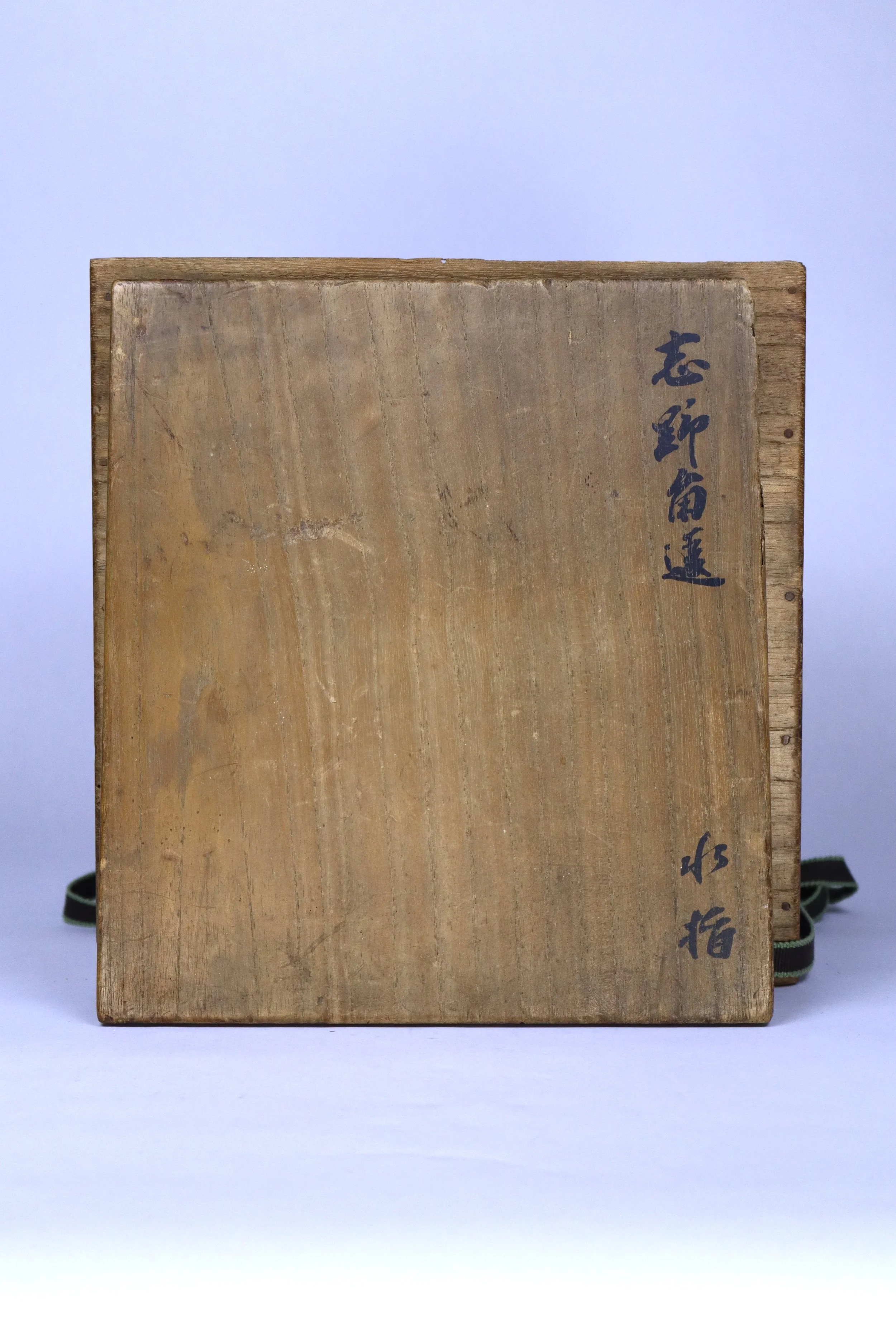 A wooden box or panel with Japanese characters written vertically on the right side.
