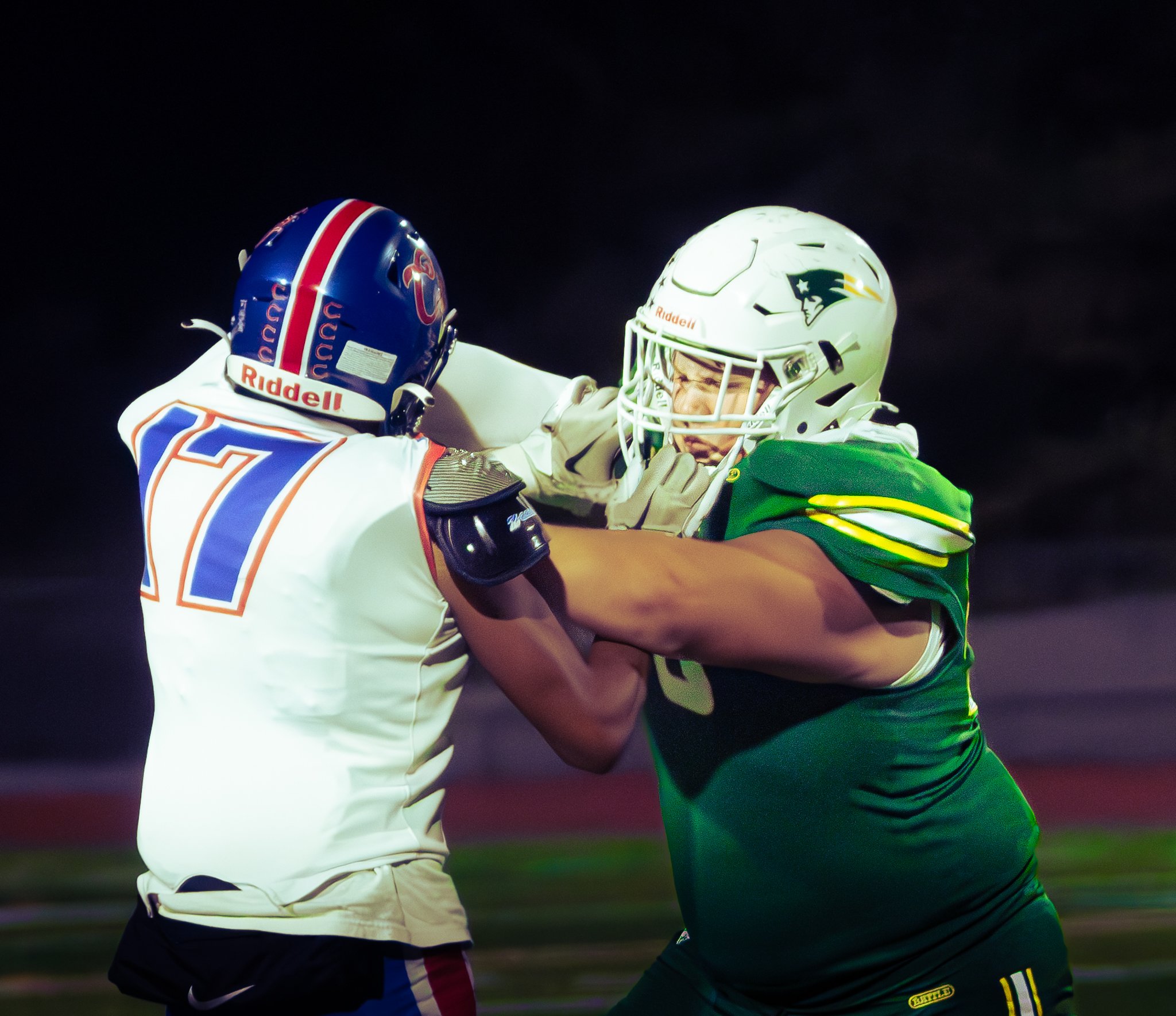 Two football players from opposing teams engaged in a confrontation on the field.