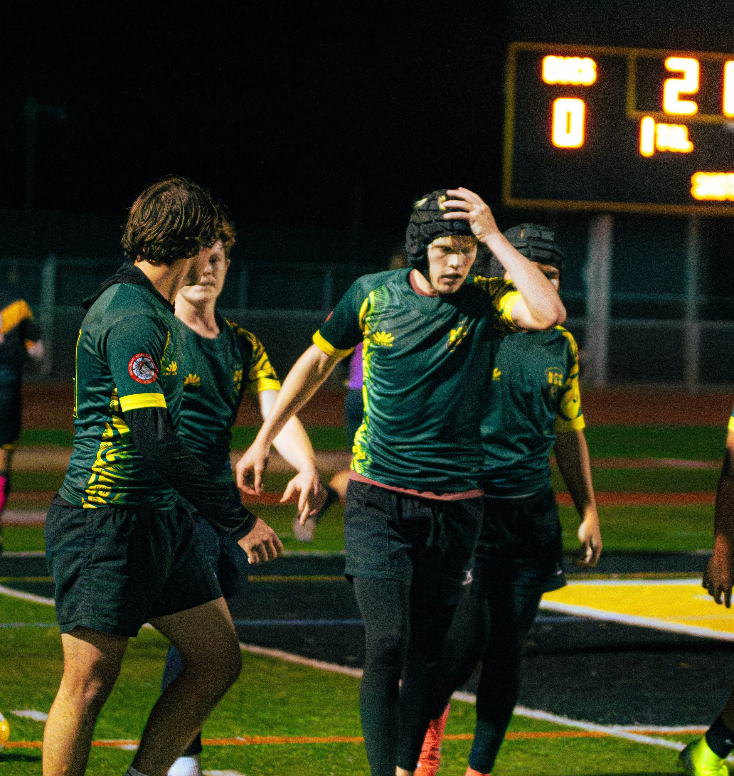 A group of athletes preparing at the start line of a race at night under stadium lights.