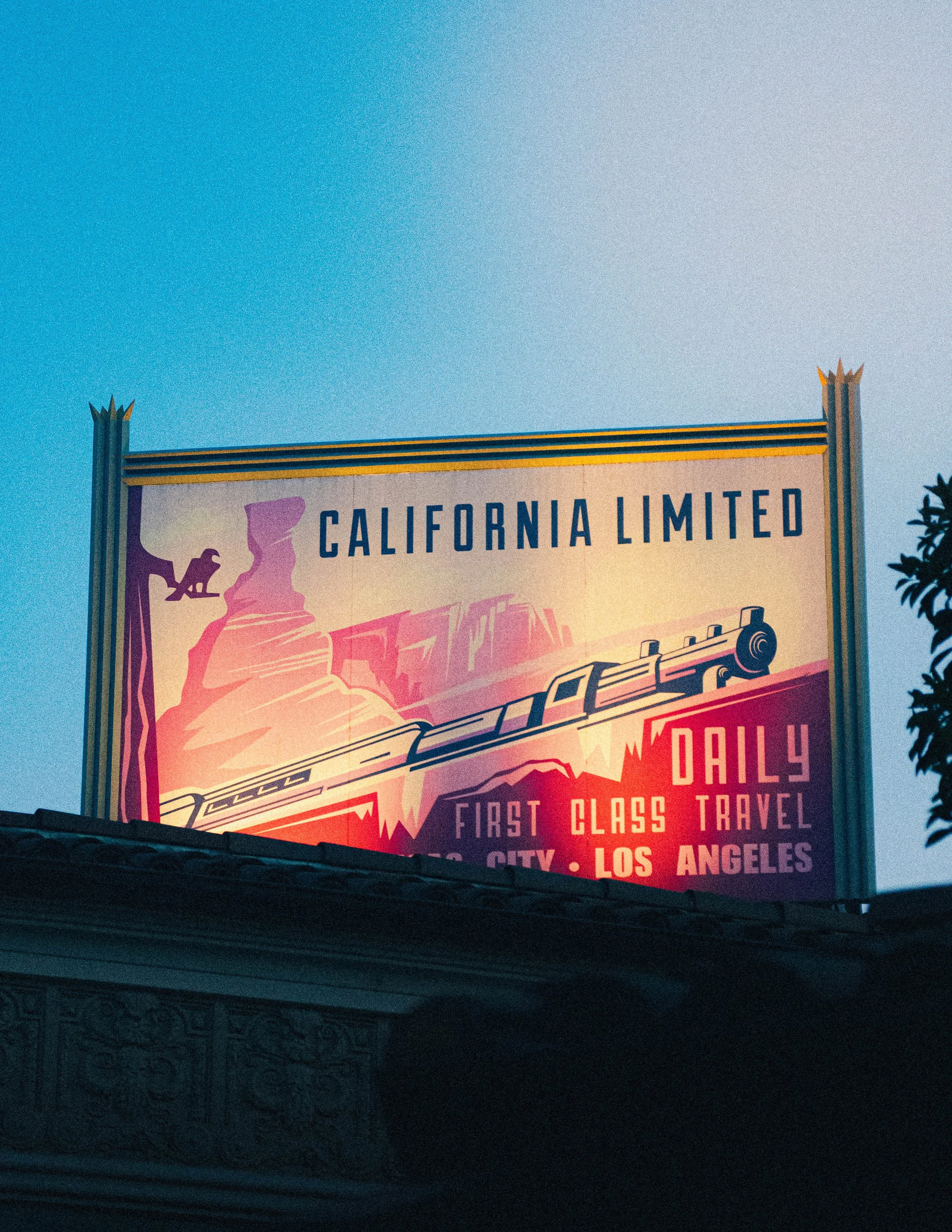 Colorful billboard advertising a travel service from Los Angeles to California, featuring a mountain and train graphic.